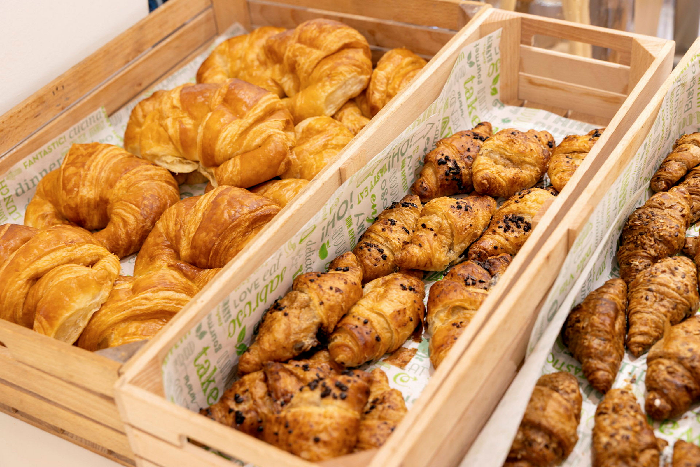 Bilde av trekasser fylt med ulike typer croissanter. (AI-generert tekst)