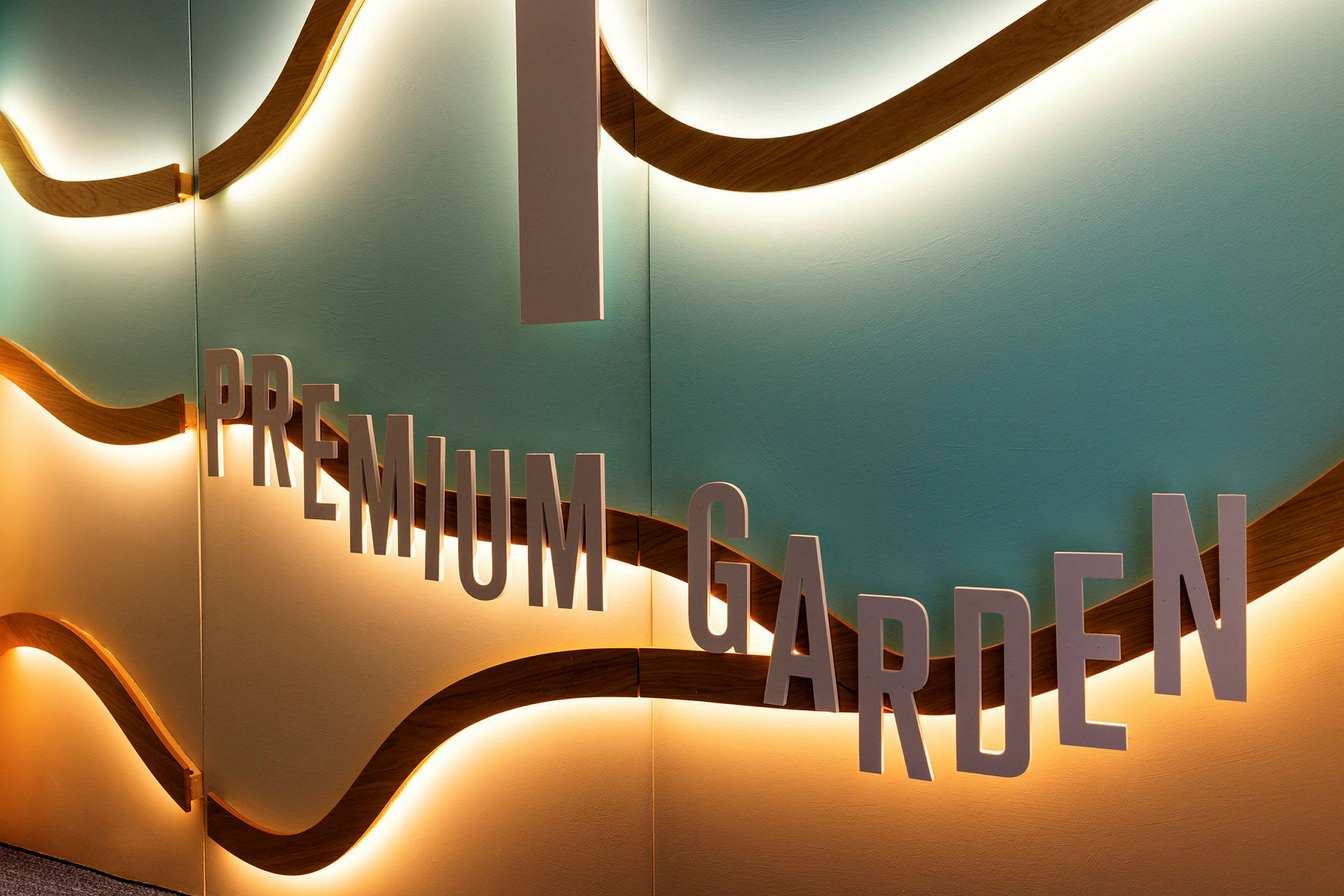 En vegg med teksten 'Premium Garden' og bølgeformede detaljer med belysning. (AI-generert tekst)