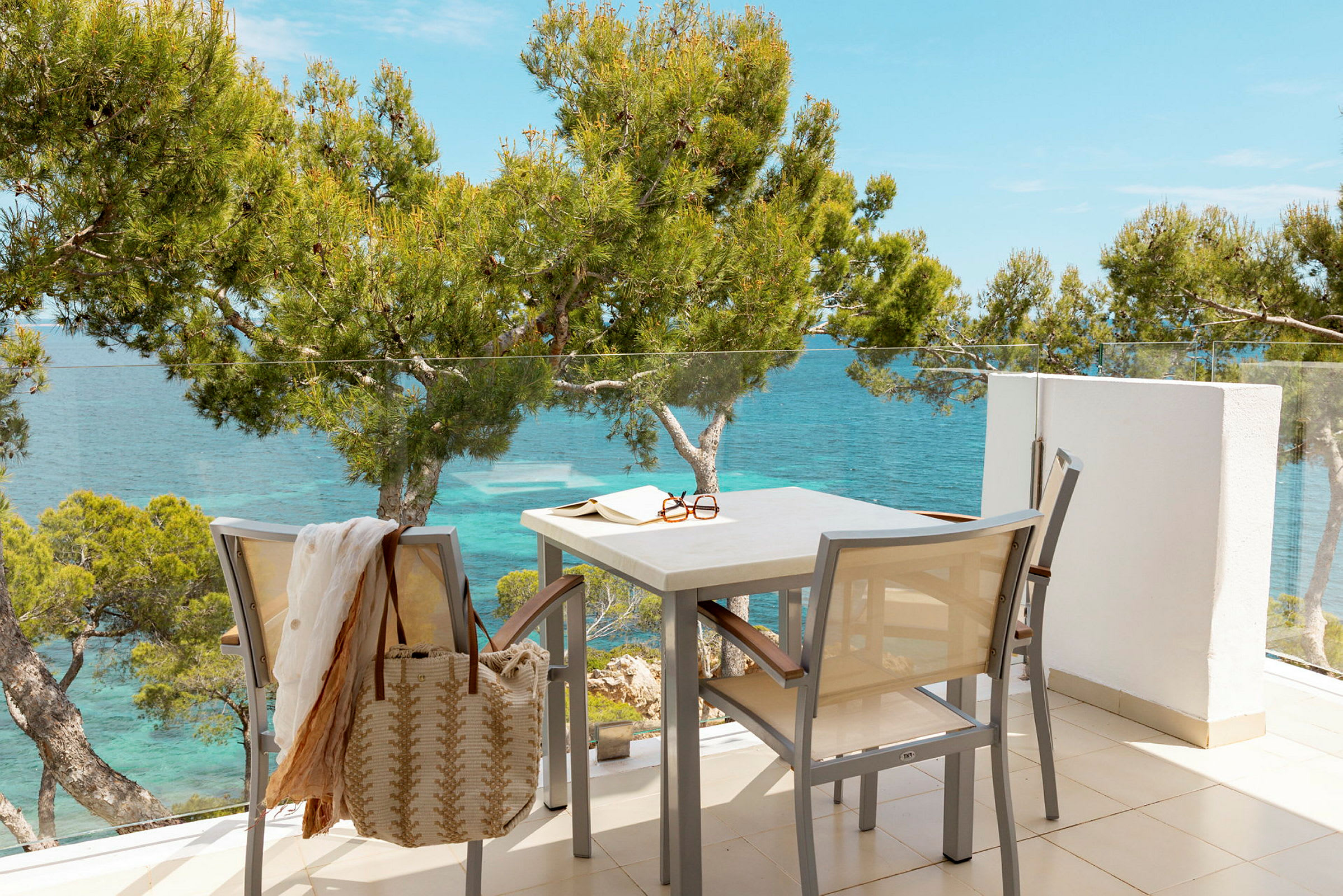 En terrasse med møbler, utsikt over havet og omkringliggende trær. (AI-generert tekst)