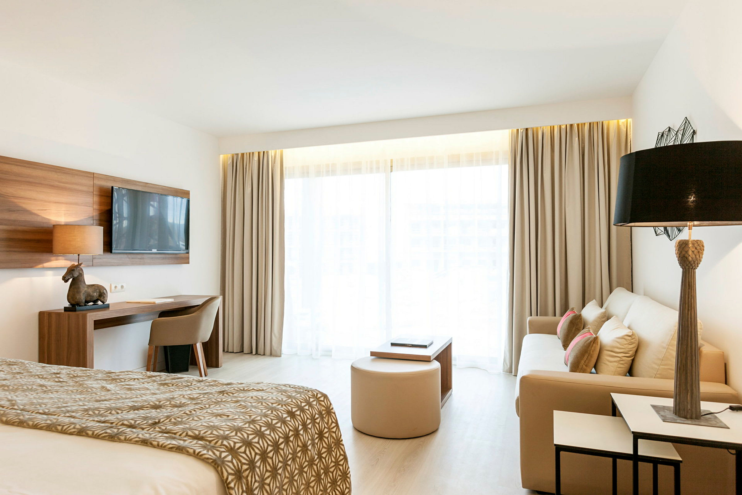 Bilde av et lyst hotellrom med seng, sofa og skrivebord. (AI-generert tekst)