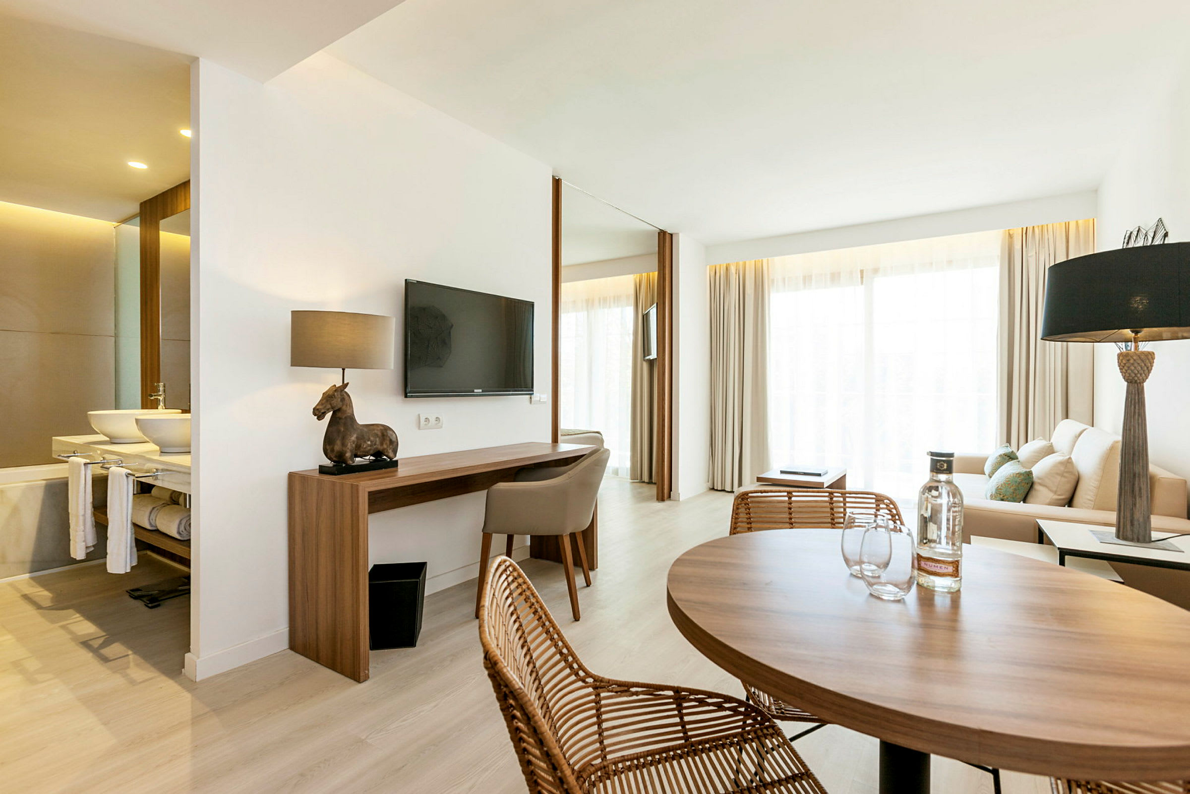 Et moderne hotellrom med sitteområde, skrivebord og bord. (AI-generert tekst)
