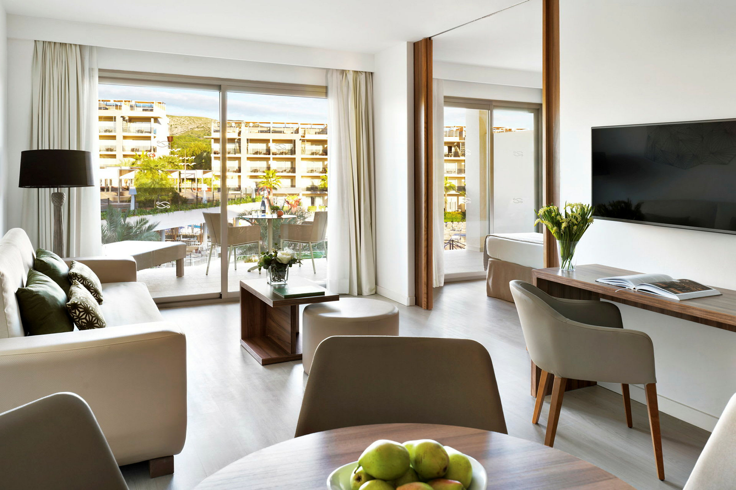 Moderne innredet hotellsuite med sittegruppe, bord og balkong. (AI-generert tekst)