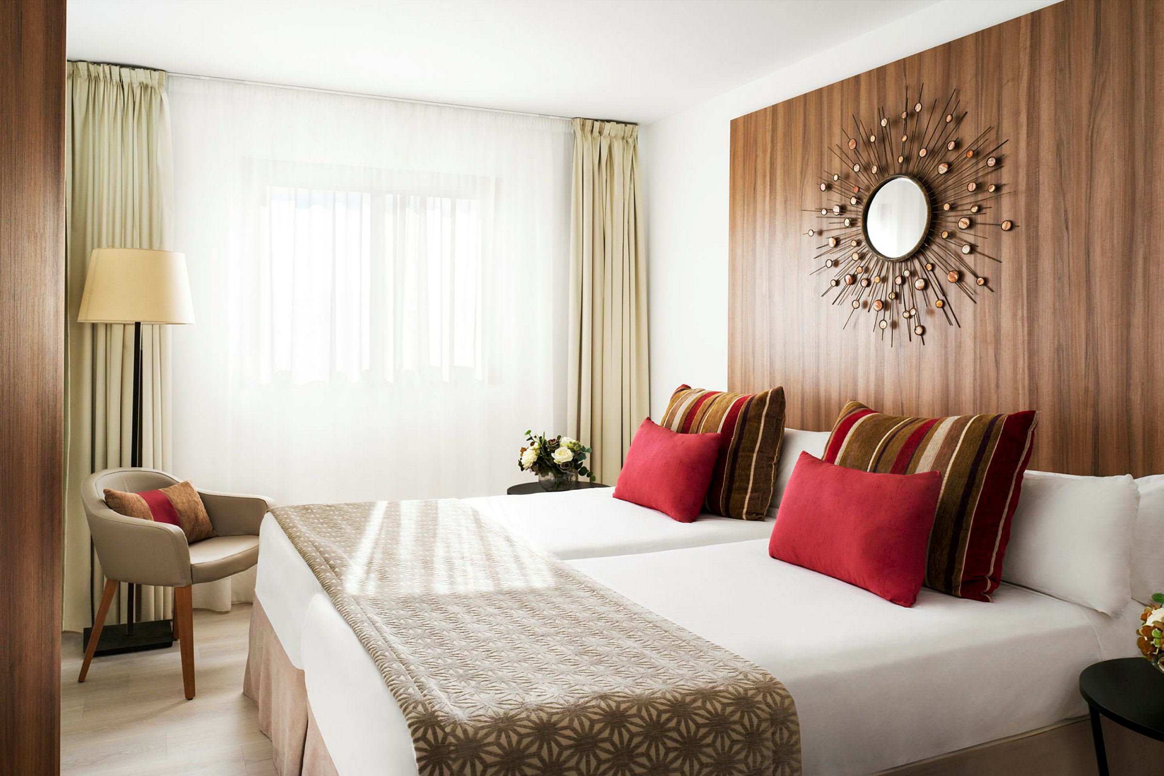 Moderne hotellrom med to senger, fargerike puter og minimalistisk innredning. (AI-generert tekst)