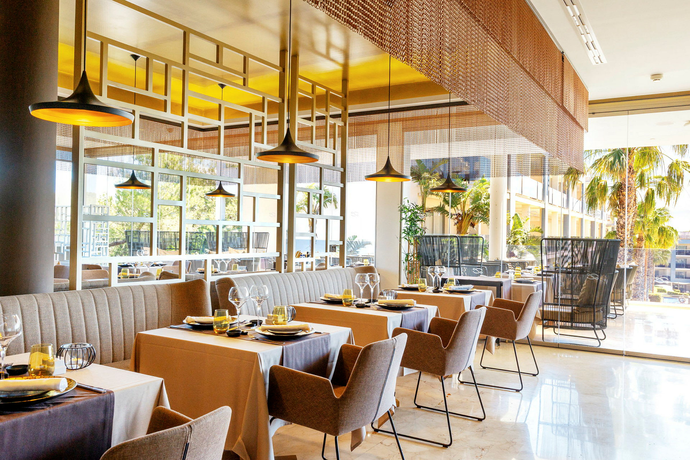 Bilde av en moderne restaurant med oppdekkede bord og stoler, store vinduer og innredning i behagelige farger. (AI-generert tekst)