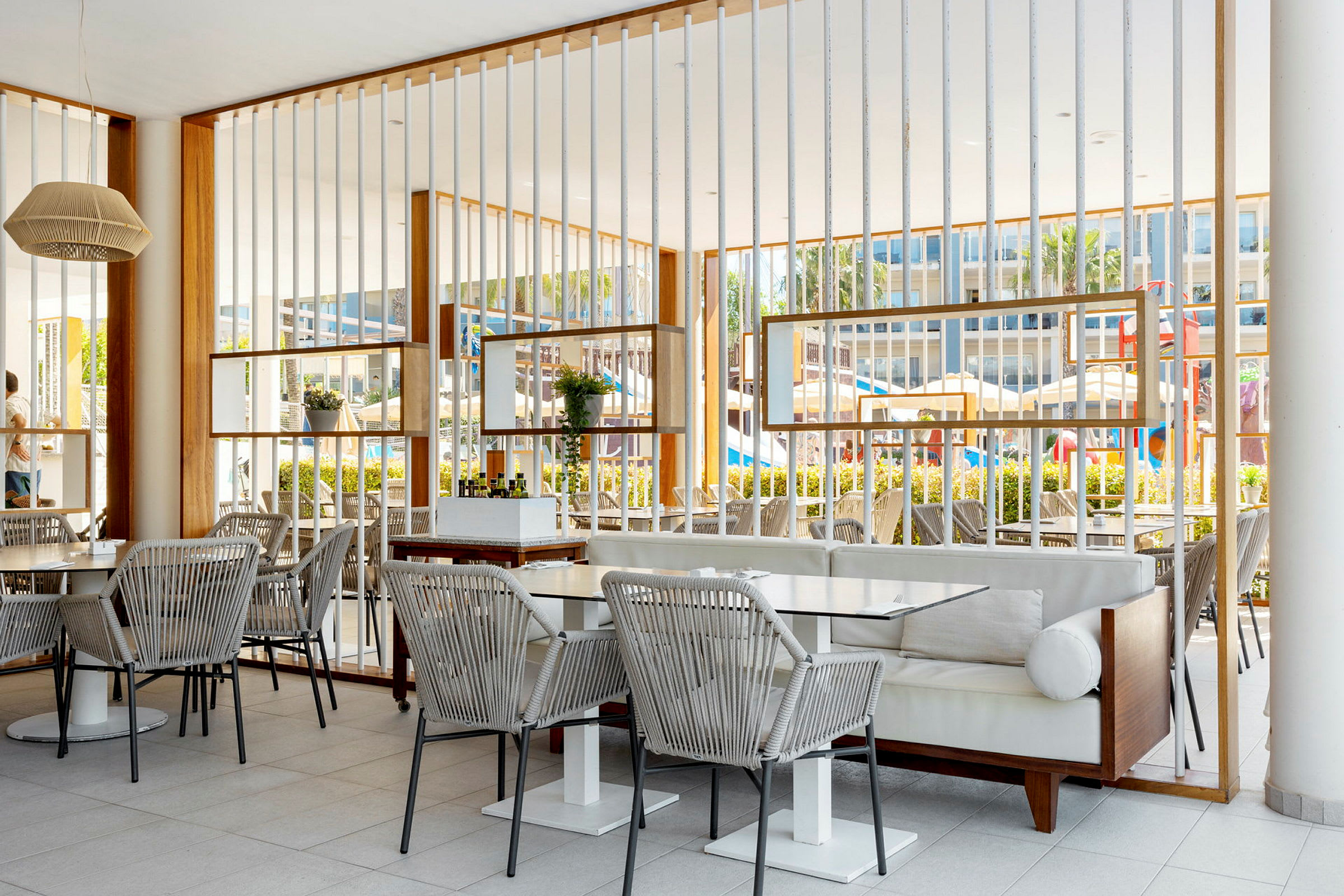 En utendørs restaurant med bord og stoler og en moderne innredning. (AI-generert tekst)