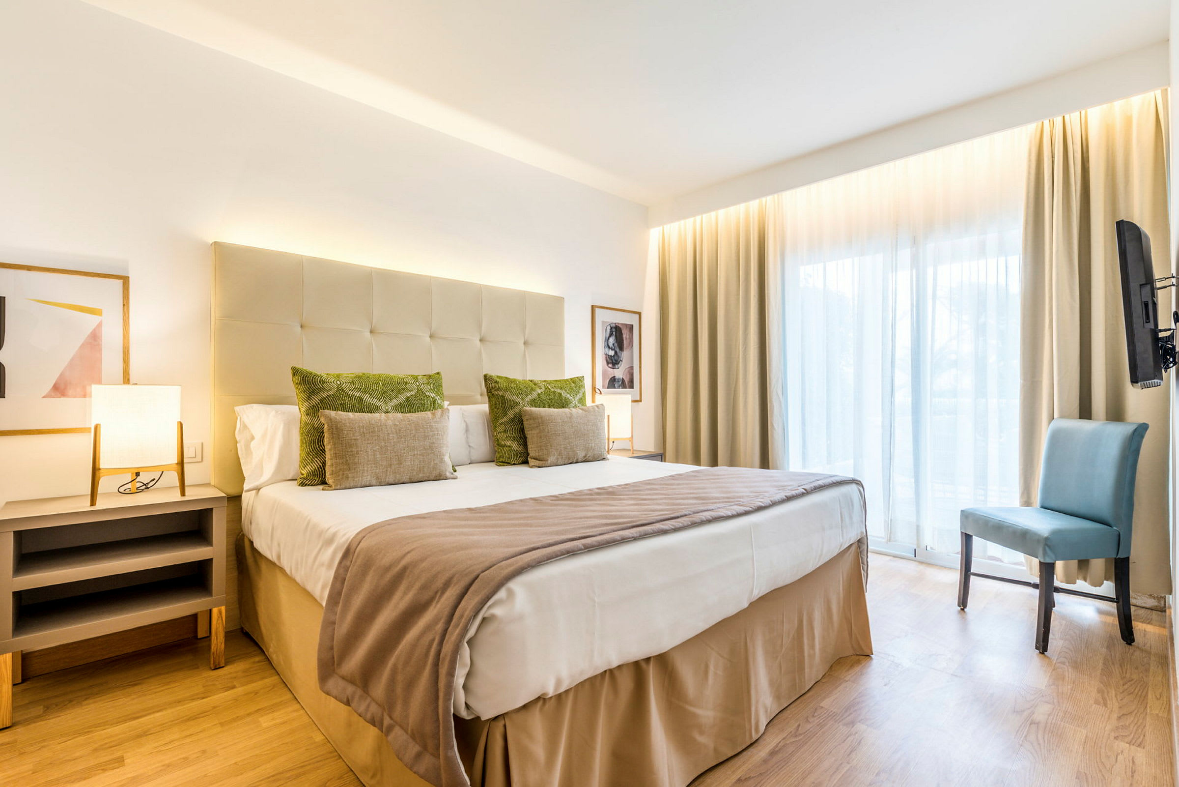 Et hotellrom med en dobbeltseng, sidebord, stol og stort vindu. (AI-generert tekst)