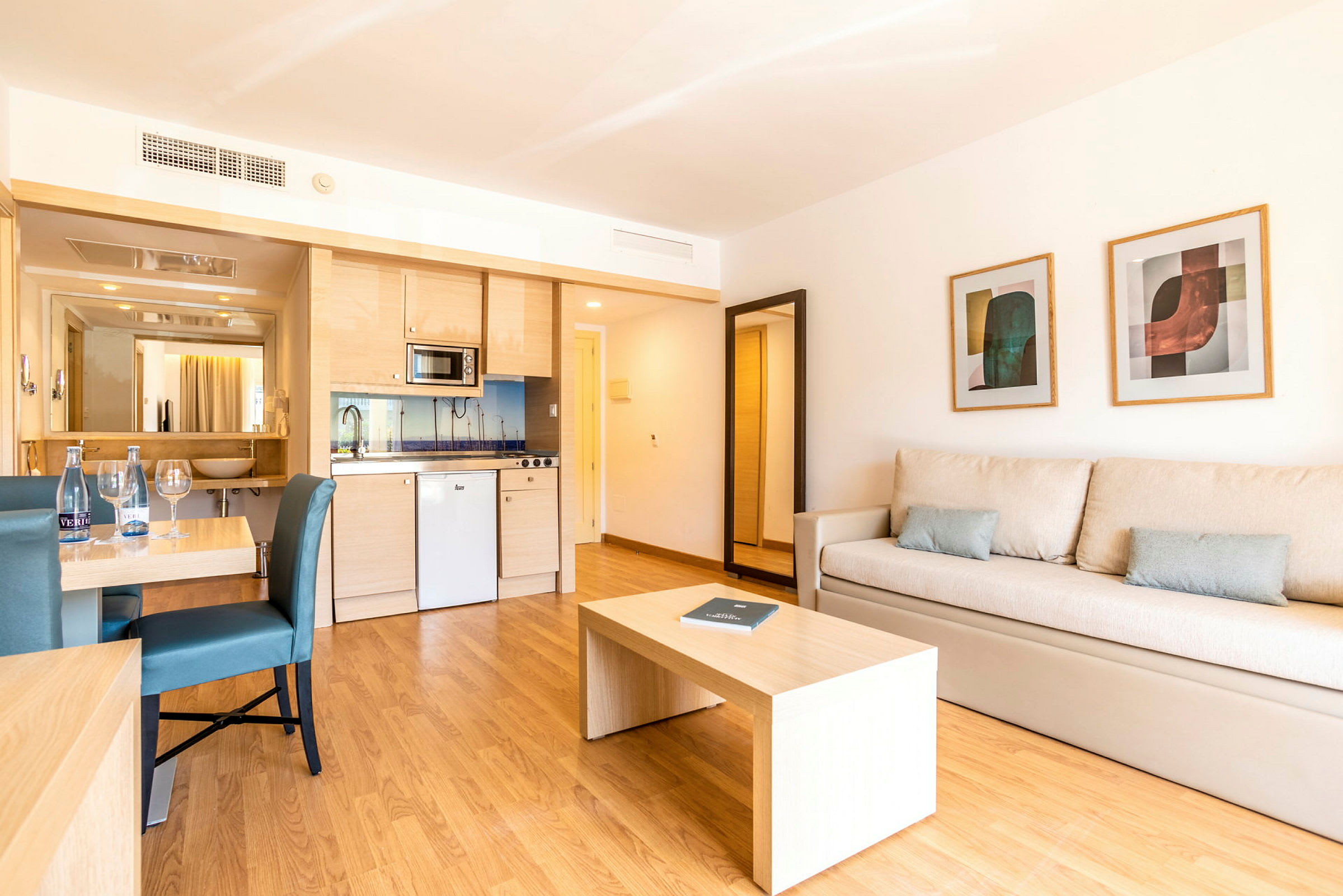 Et hotellrom med kjøkken, spisebord og sofa. (AI-generert tekst)