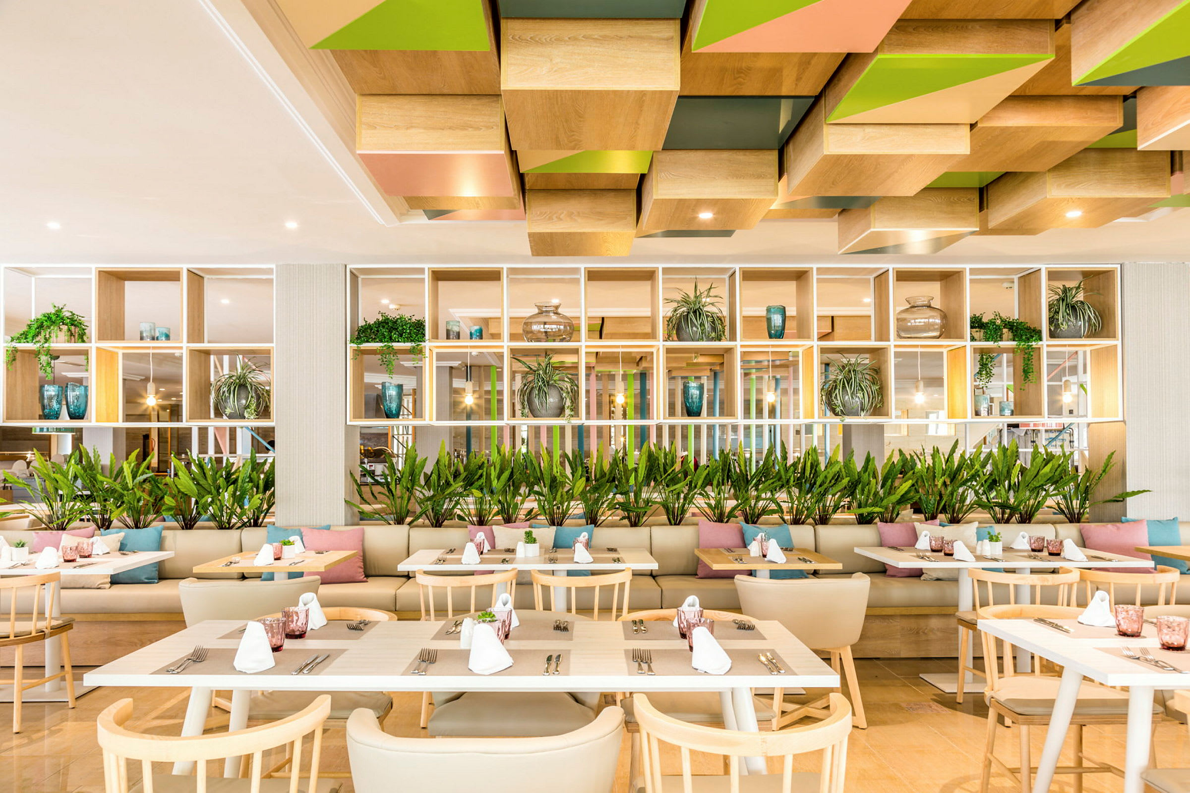 Moderne restaurant med trebord, stoler og dekorasjoner som inkluderer planter og puter. (AI-generert tekst)