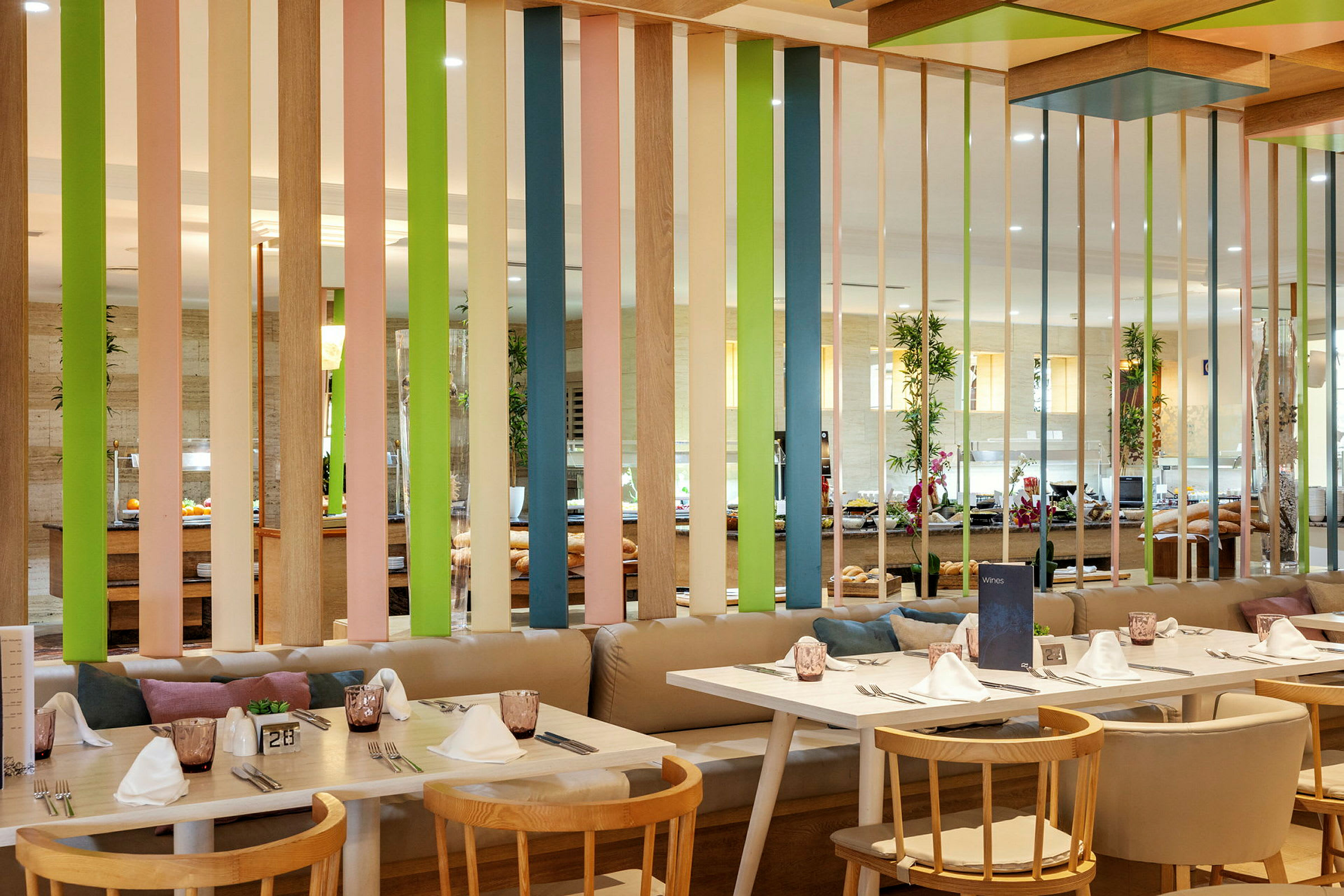 Interiør av en restaurant med bord, stoler og en fargerik skjermvegg. (AI-generert tekst)
