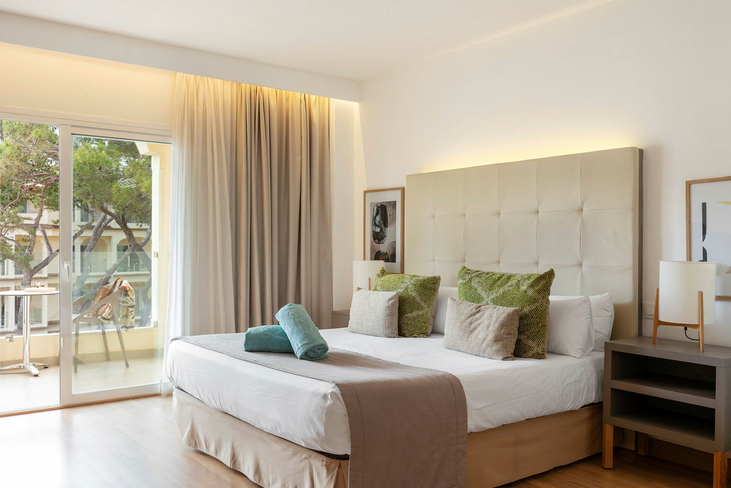 Hotellrom med dobbeltseng, innredning i nøytrale farger og en balkong med utsikt. (AI-generert tekst)