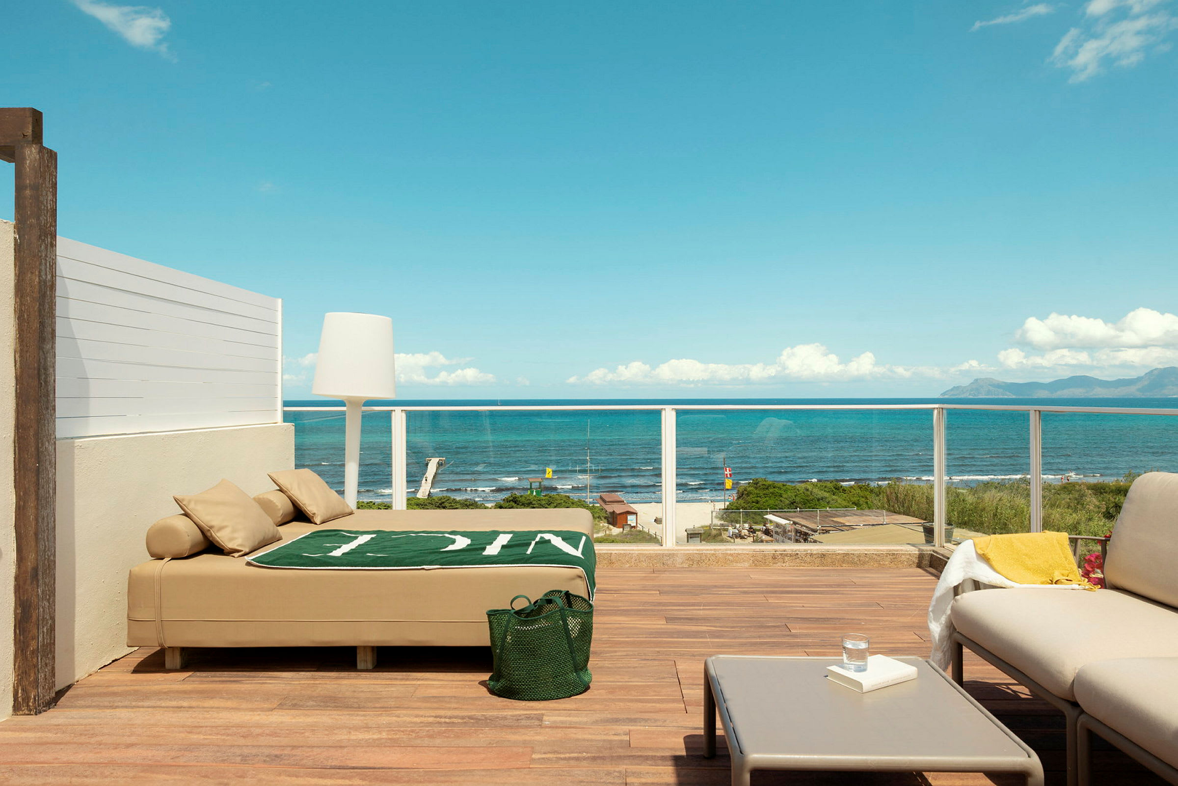 Terrasse med moderne møblering og utsikt over havet, inklusive en solseng, sofamøbler og bord. (AI-generert tekst)