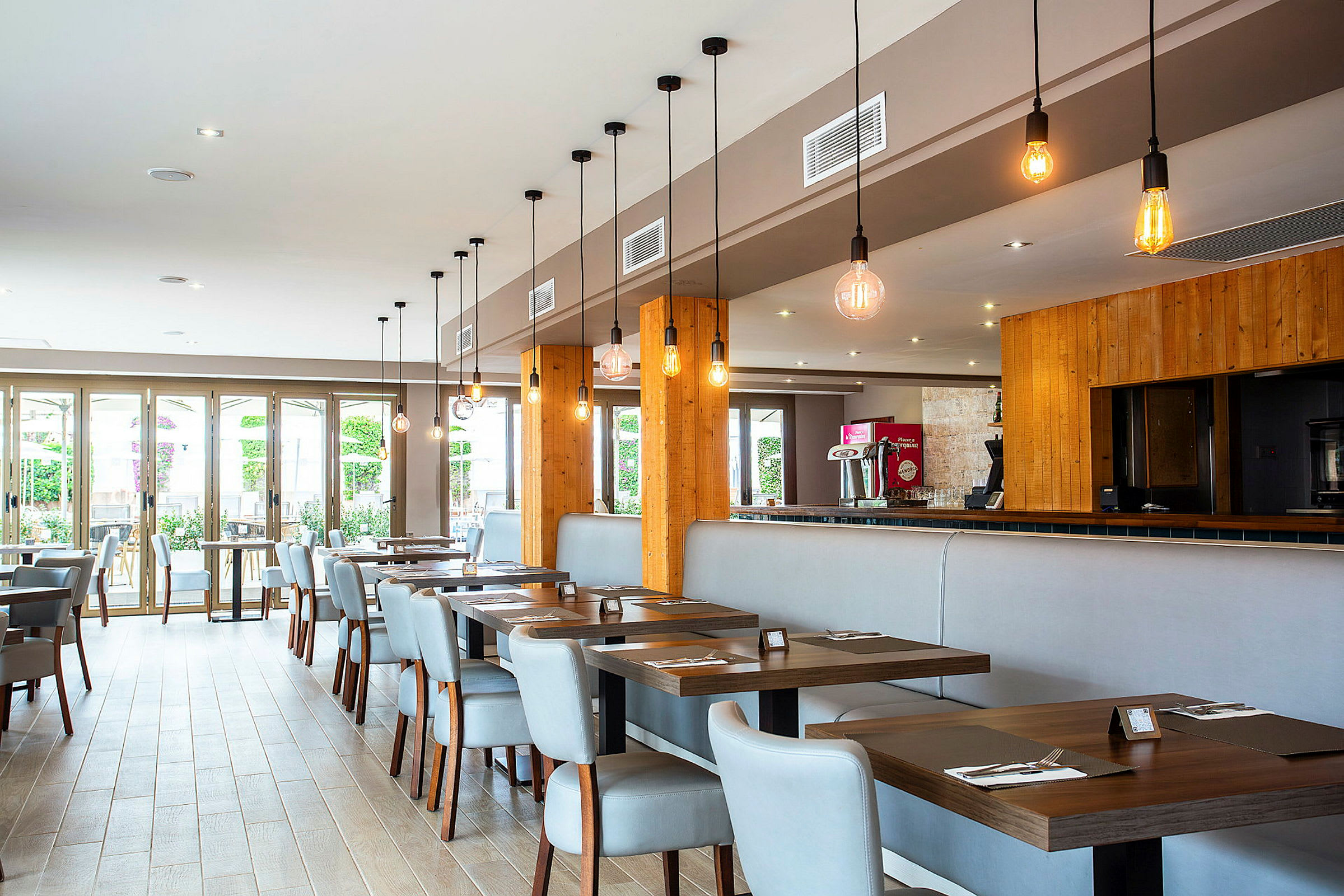 Moderne restaurantbord med stoler i lyst interiør og hengende lamper. (AI-generert tekst)