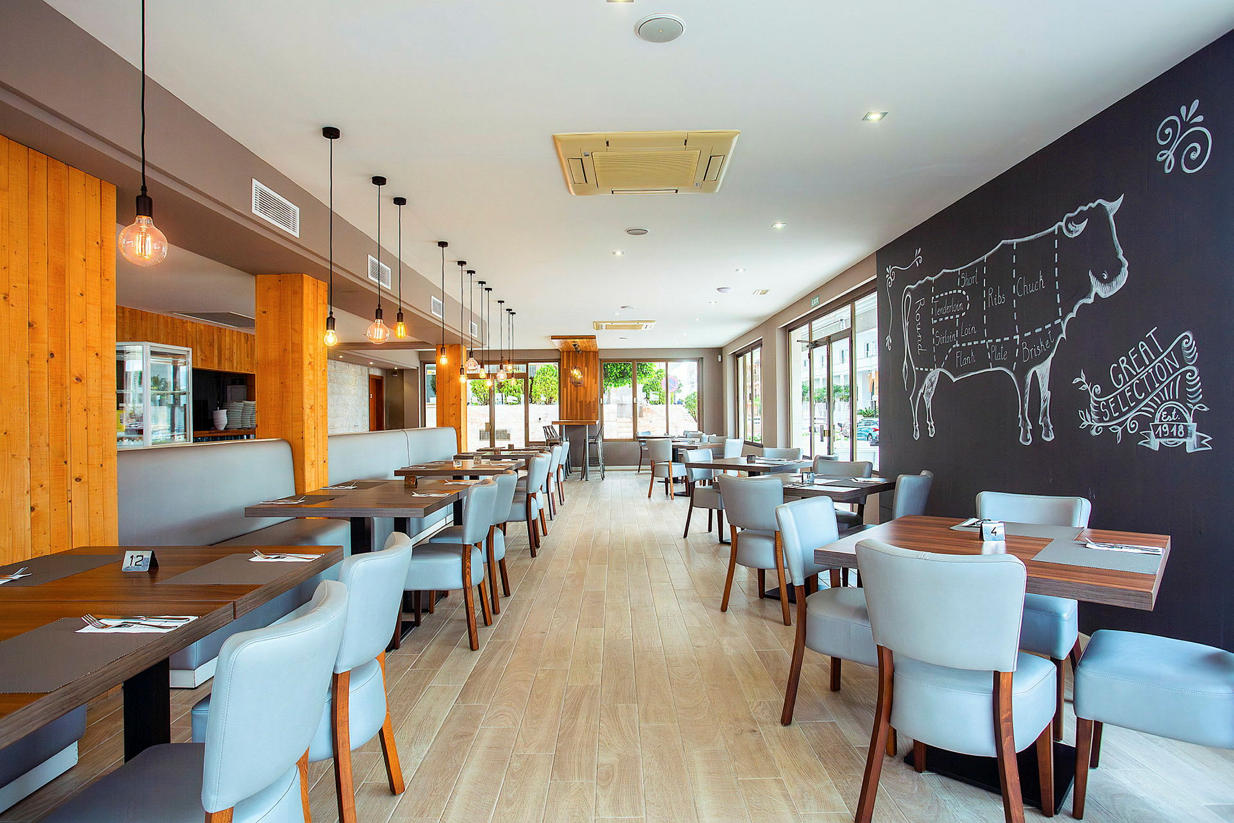 Restaurantinteriør med bord og stoler, vegg med tegning av en ku. (AI-generert tekst)