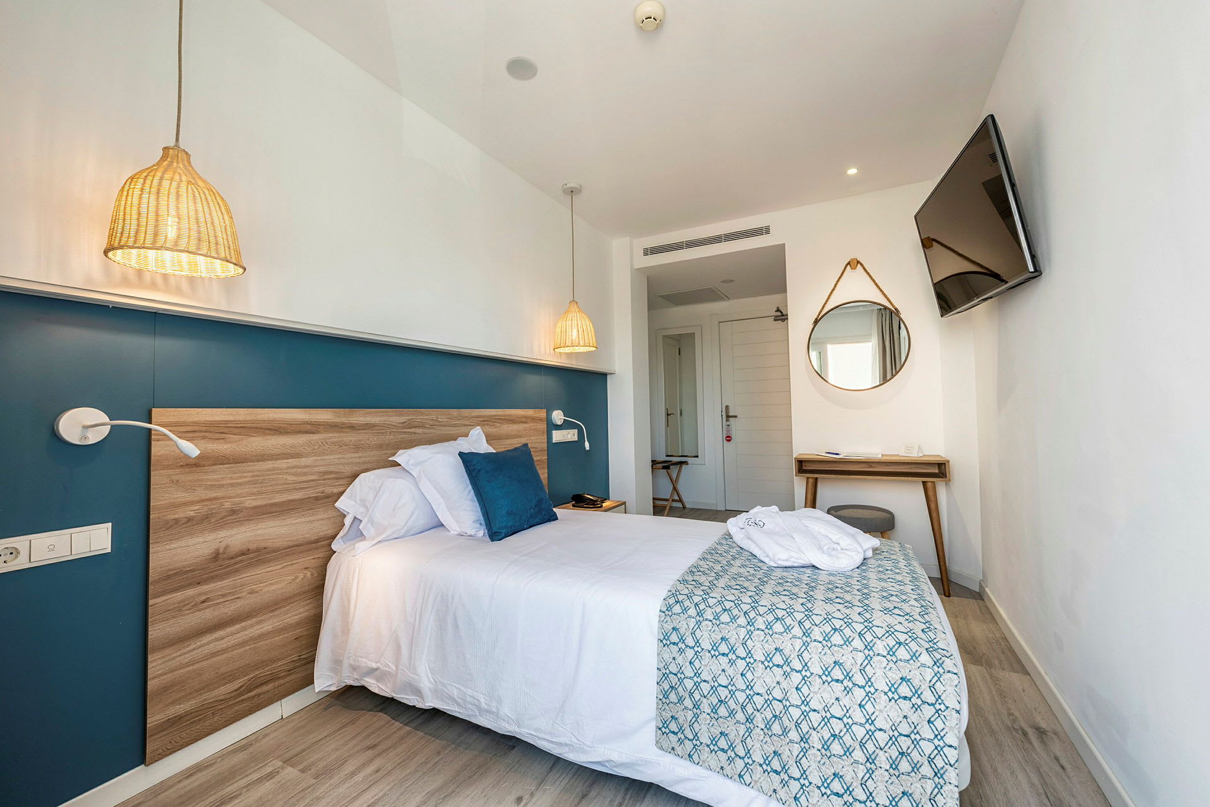 Moderne hotellrom med seng, speil og TV. (AI-generert tekst)