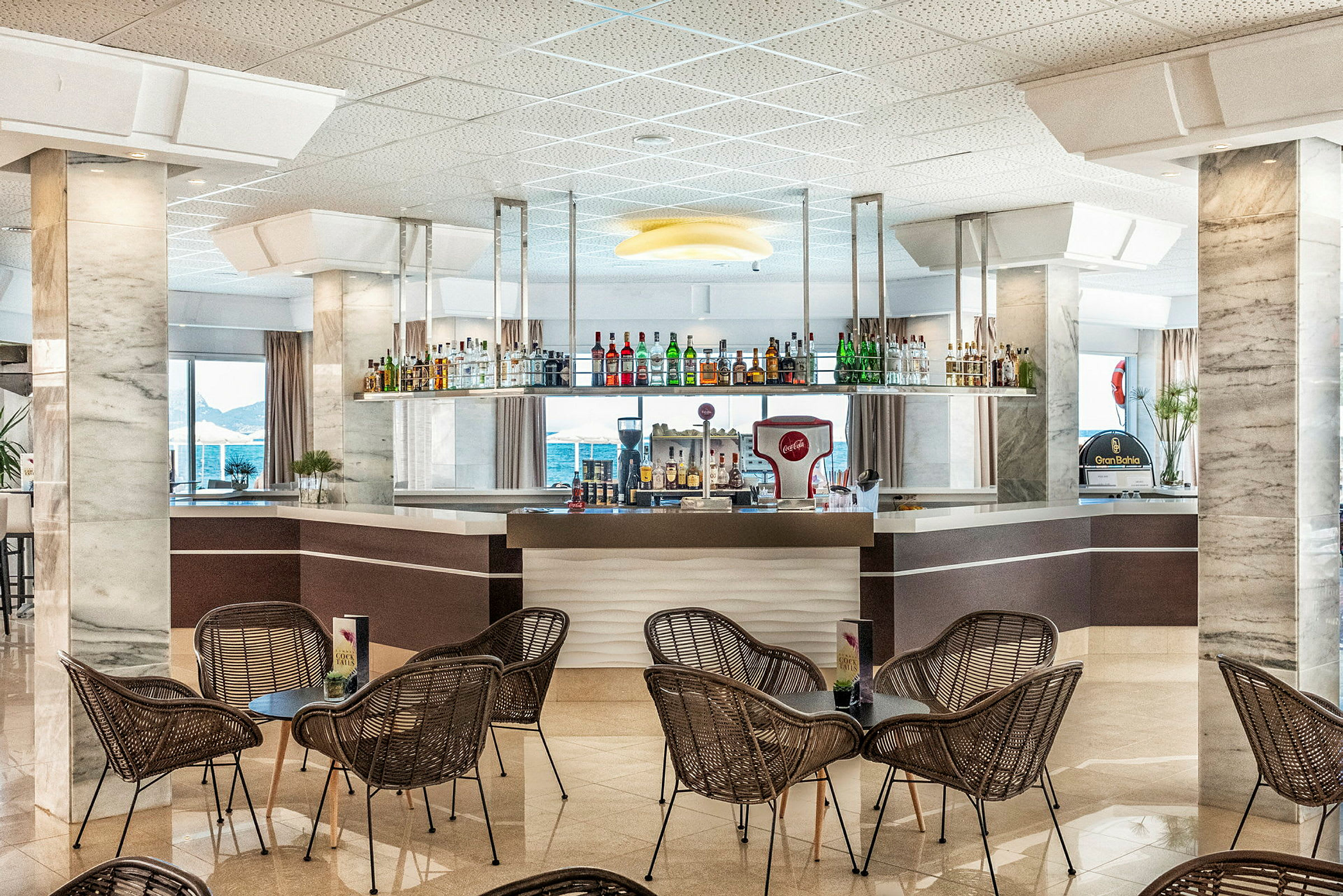 Hotellbar med stoler og bord i forgrunnen. (AI-generert tekst)