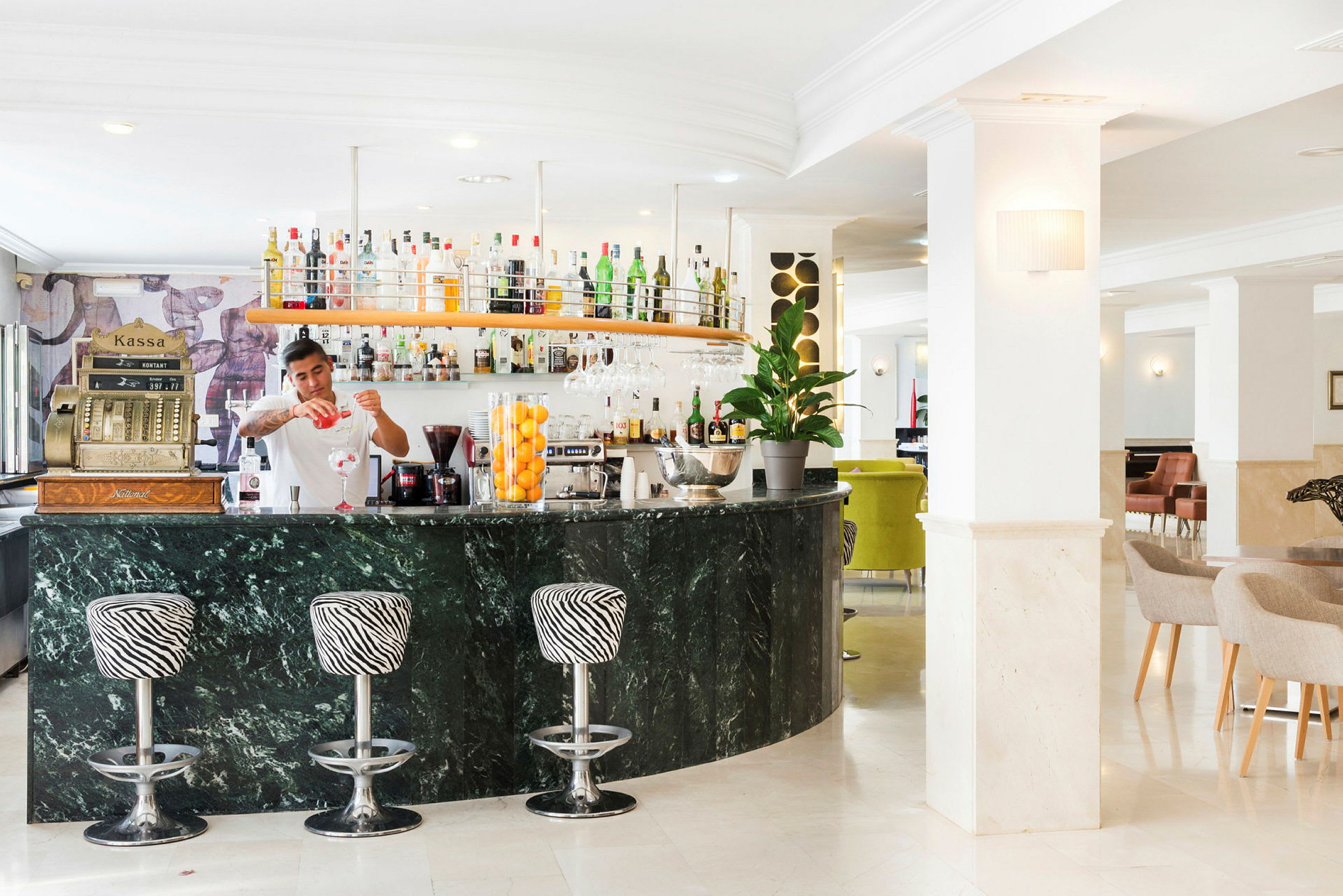 En godt opplyst hotellbar med marmordisk og sebramønstrede barkrakker. (AI-generert tekst)
