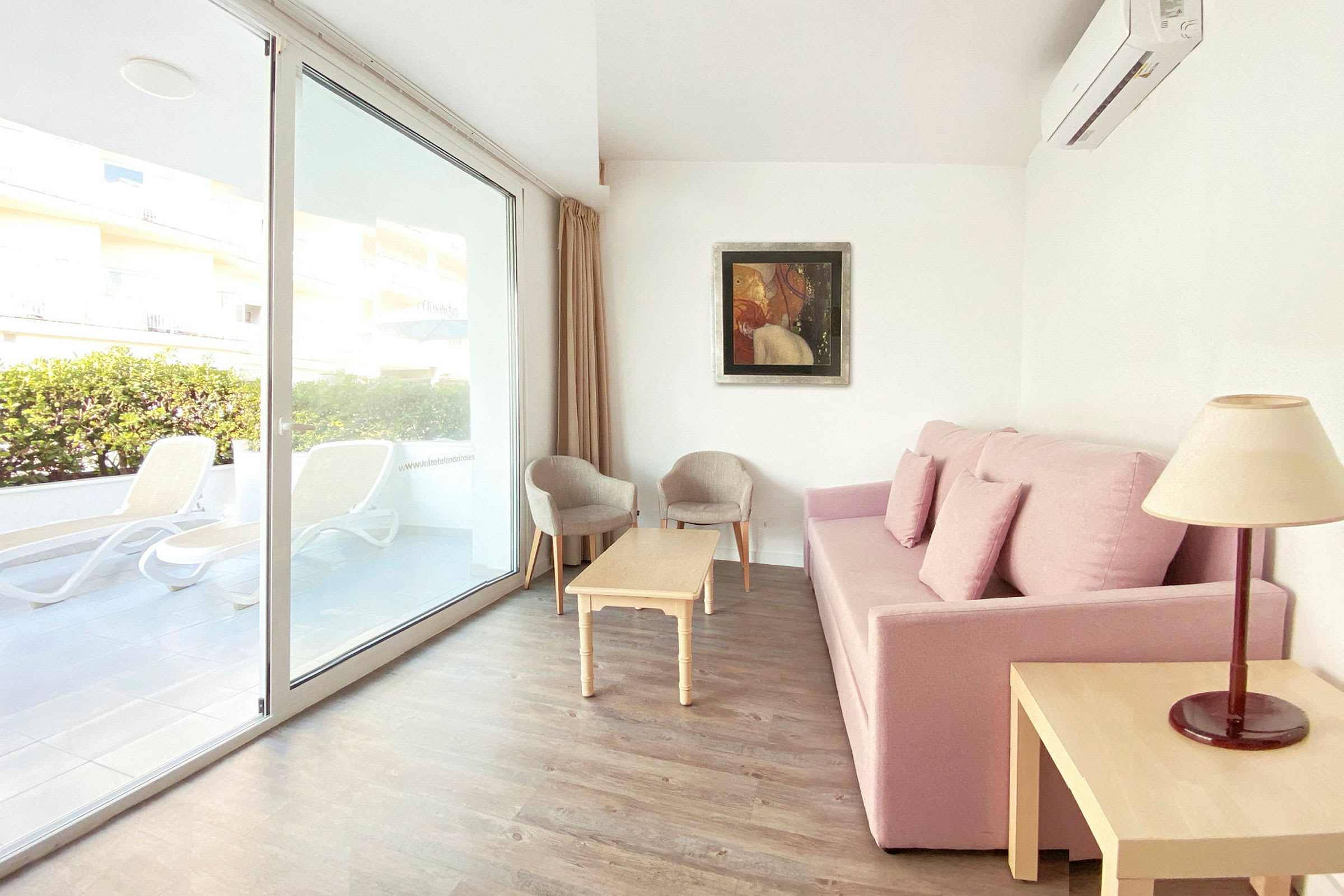 Sofa med rosa trekk, stuebord, to stoler og vindu med utsikt mot terrassen. (AI-generert tekst)