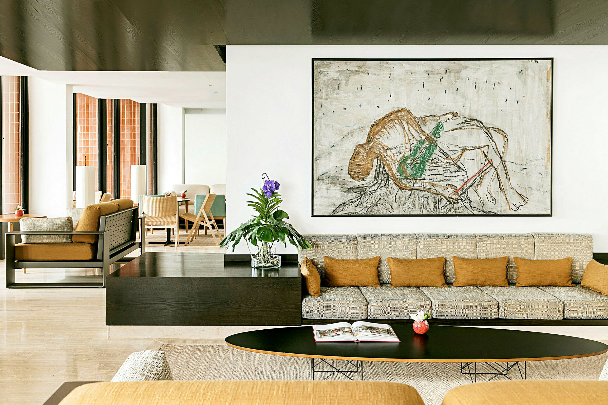 En moderne stue med beige sofa, oransje puter og et stort kunstverk på veggen. En grønn plante i en glassvase står på bordet. (AI-generert tekst)