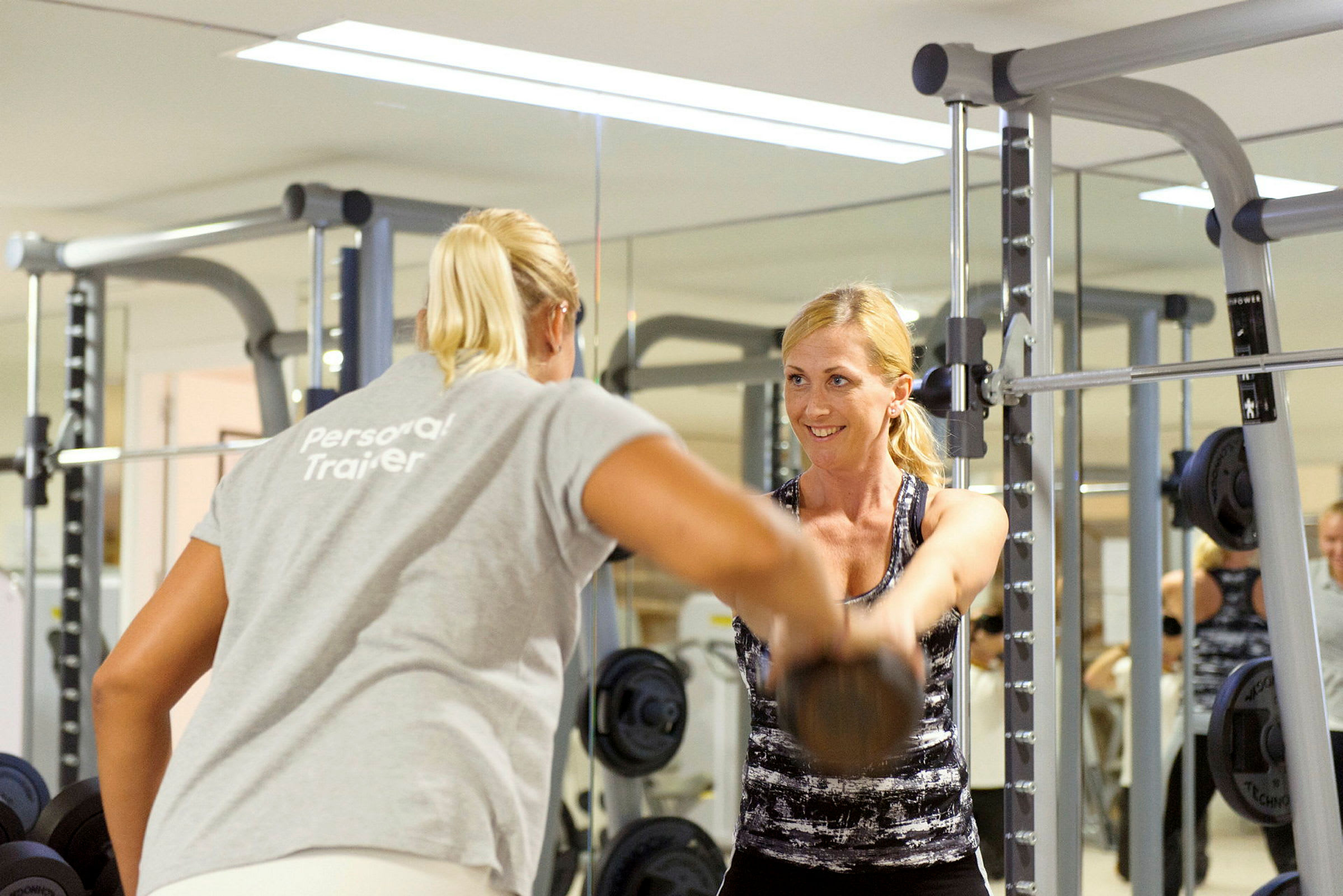 Personlig trener hjelper en kvinne med trening med manualer på et treningsstudio. (AI-generert tekst)