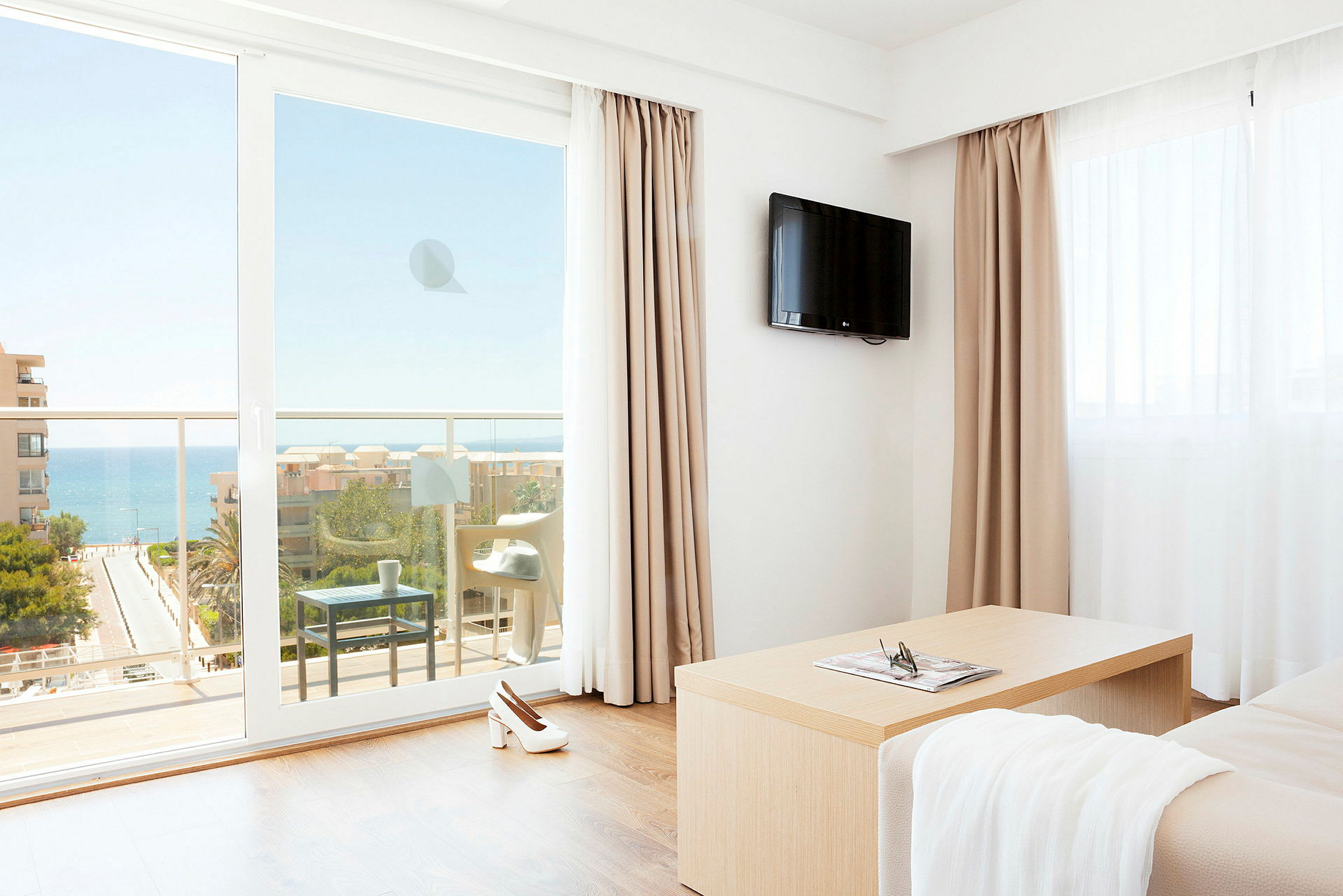 Et hotellrom med utsikt over havet gjennom en balkong. (AI-generert tekst)