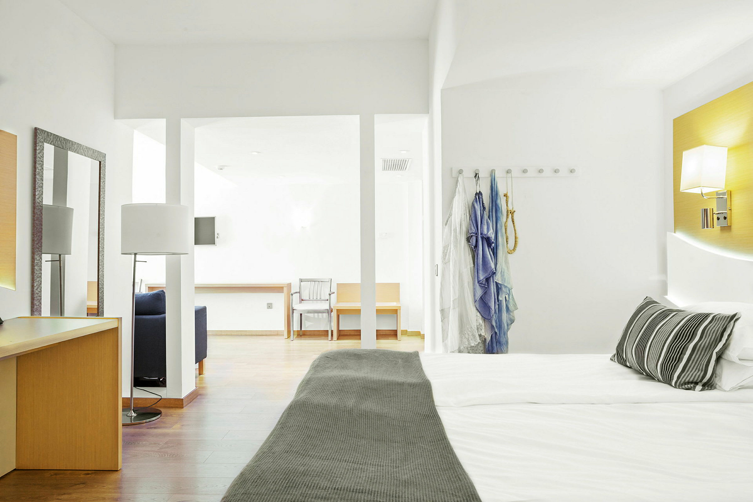 Hotellrom med en dobbeltseng, skrivebord og sittemøbler. (AI-generert tekst)