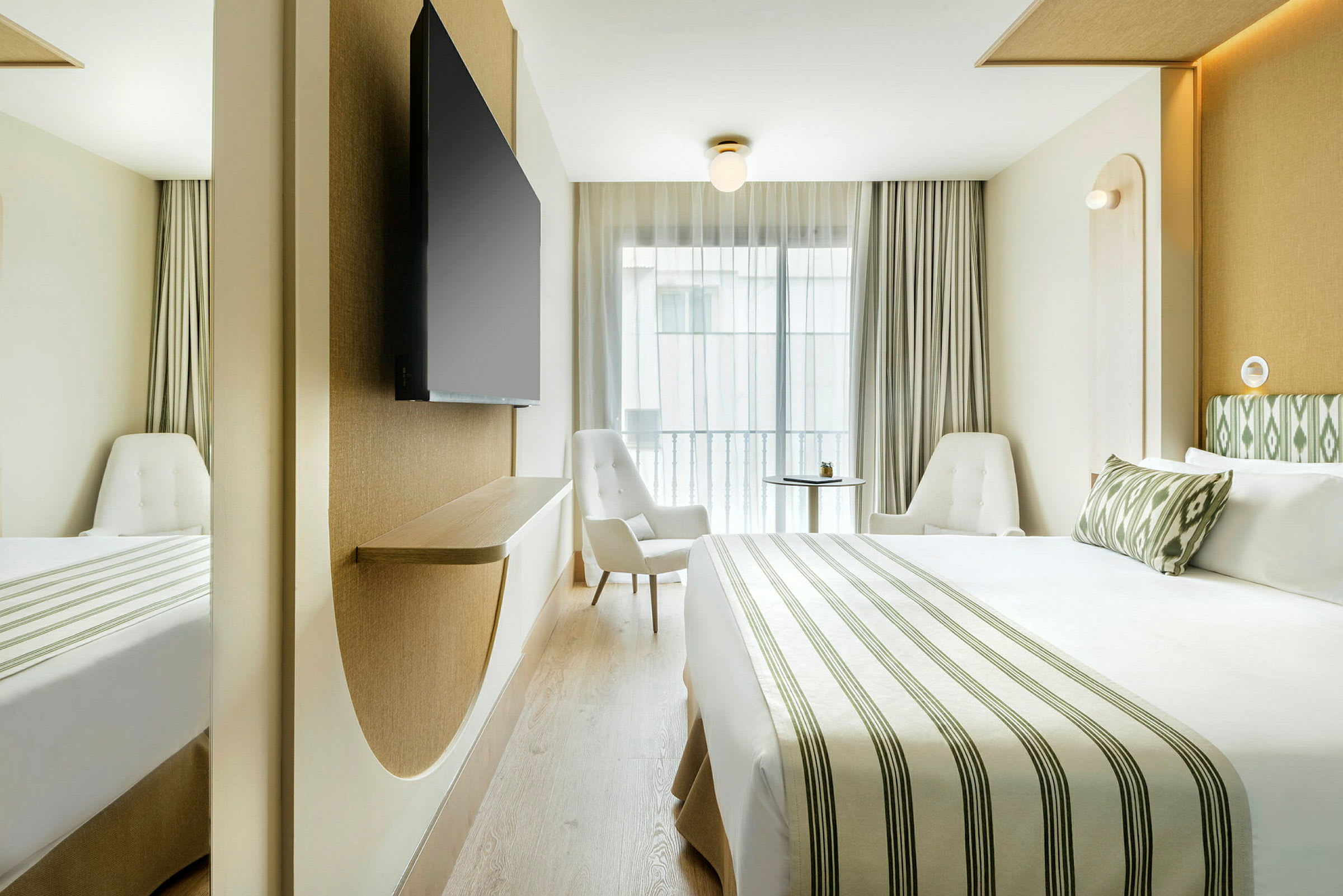 Et moderne hotellrom med en stor seng, to stoler og en veggmontert TV. (AI-generert tekst)