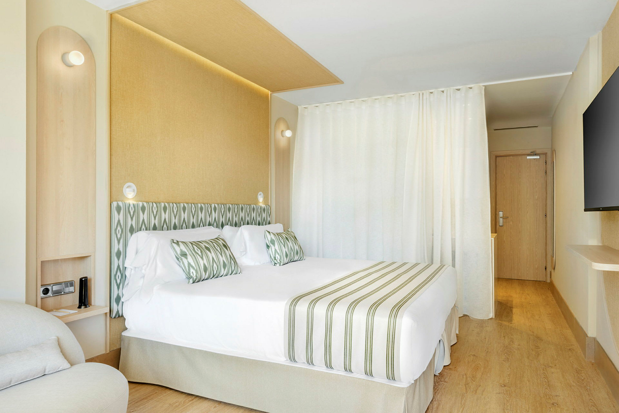 Hotellrom med dobbeltseng, grønn-hvit stripet innredning og lyse møbler. (AI-generert tekst)