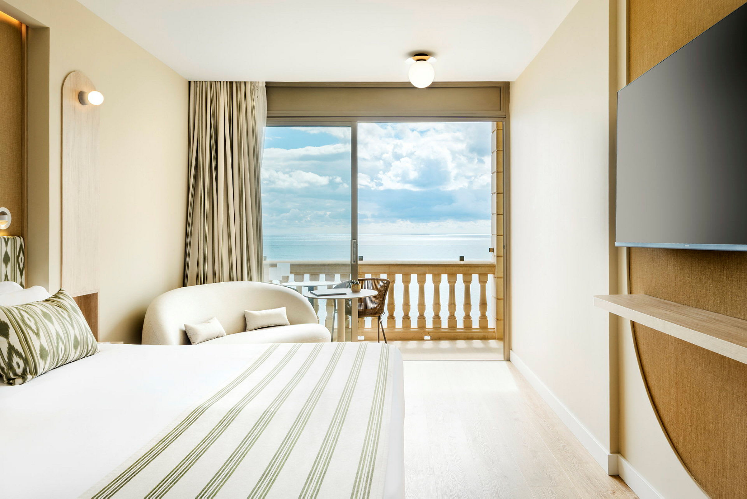 Et hotellrom med havutsikt fra balkongen. Et stort vindu vender mot havet. (AI-generert tekst)