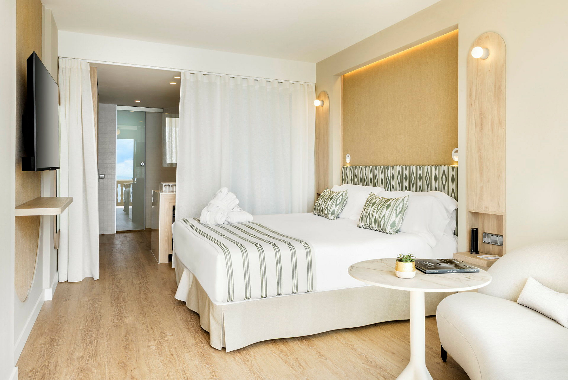 Bilde av et moderne hotellrom med dobbeltseng, sitteområde og åpning mot baderom. (AI-generert tekst)