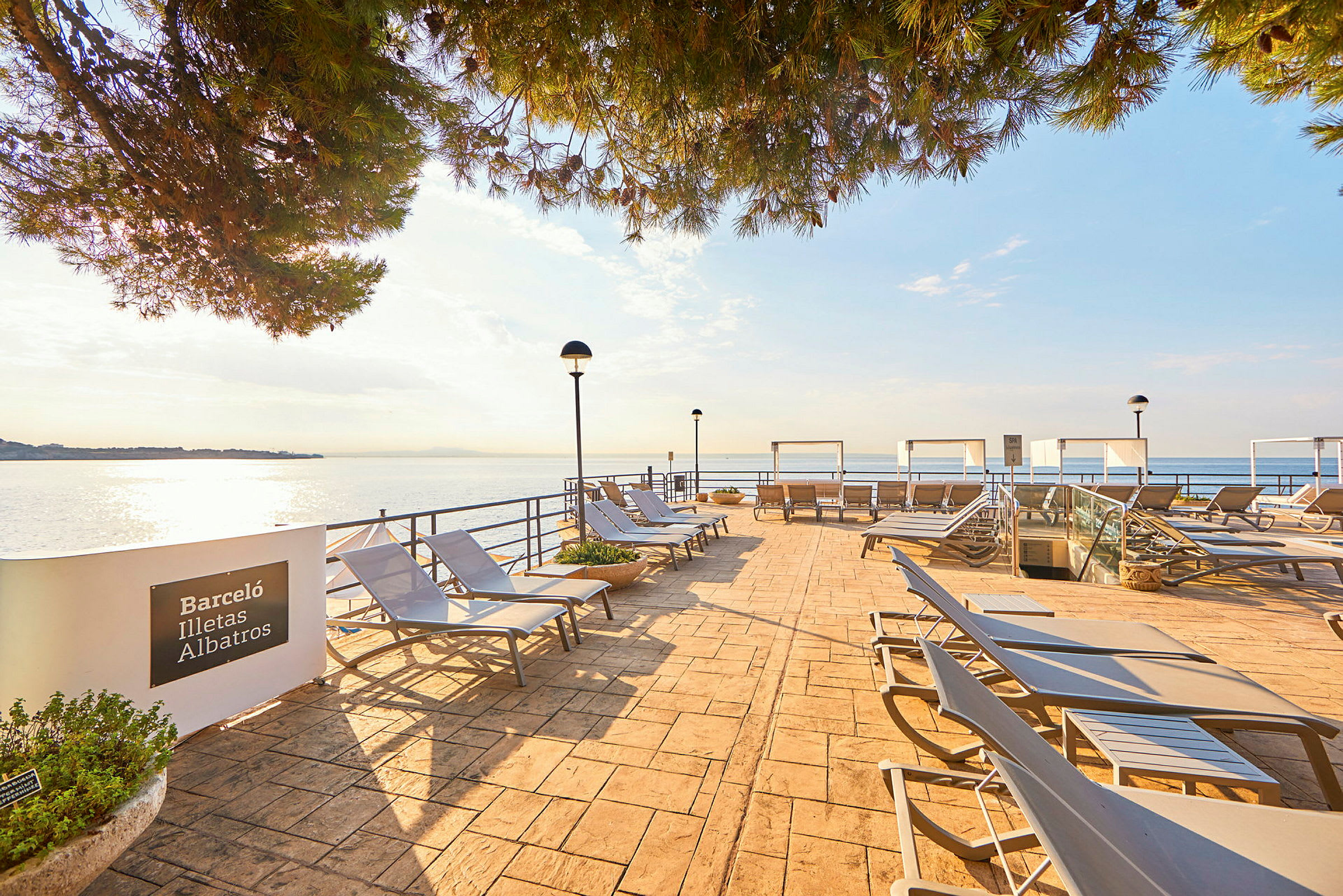 En utendørs terrasse med solsenger og utsikt over havet. (AI-generert tekst)