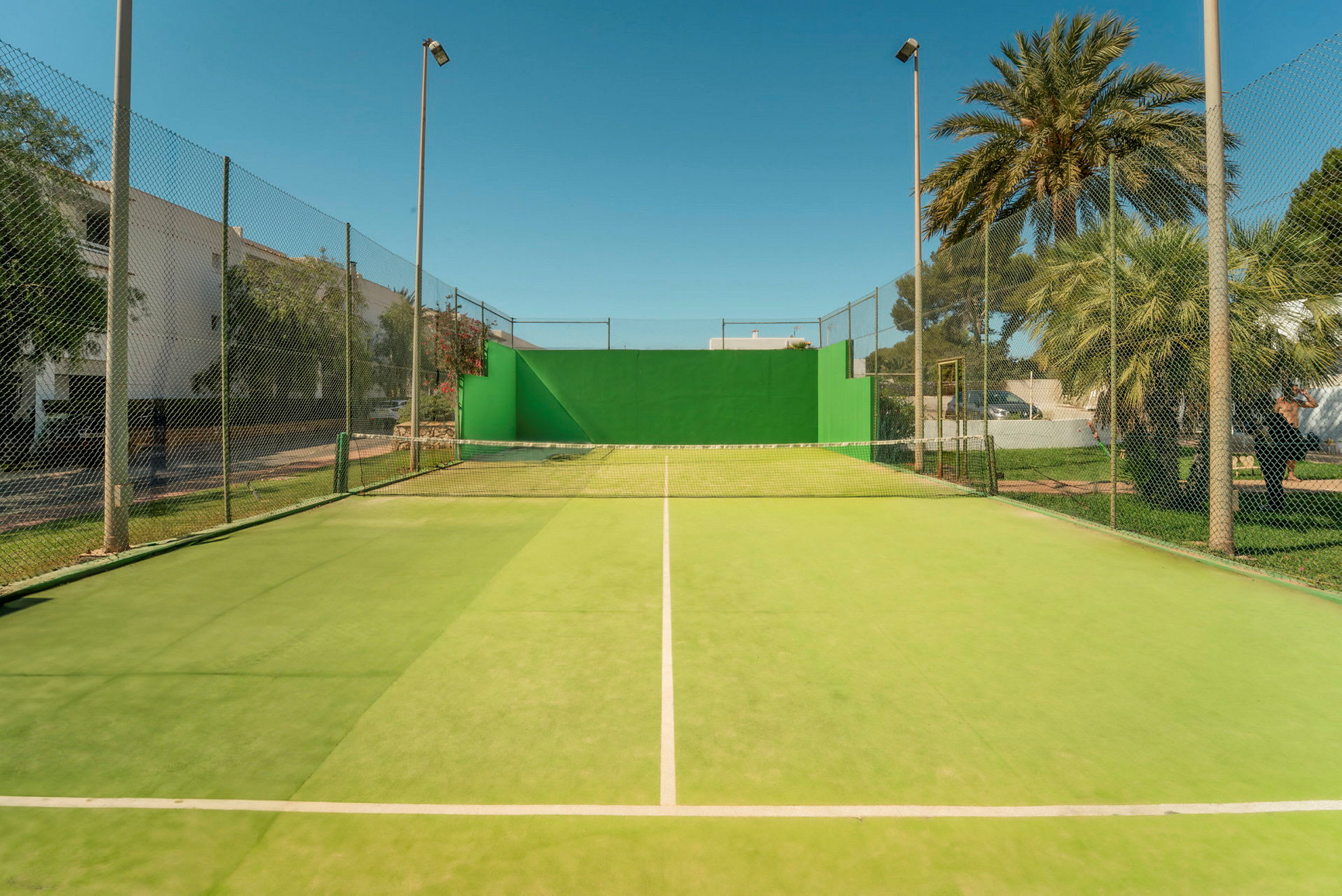 Tennisbane med grønt underlag og nett. (AI-generert tekst)