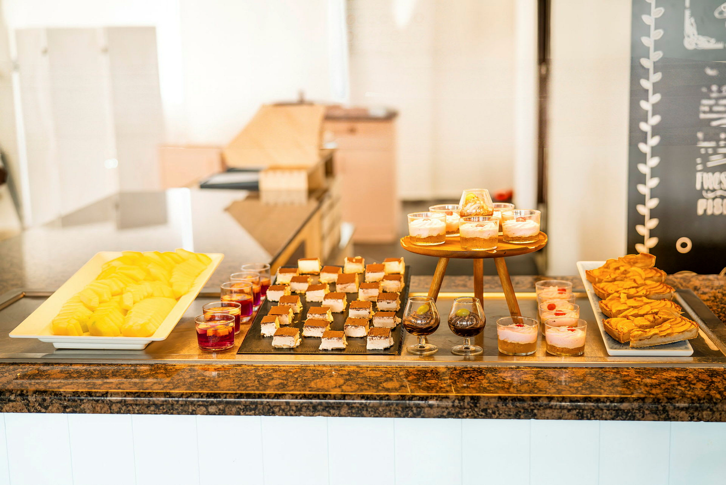 Buffet med forskjellige desserter som oppskåret frukt, bakverk og dessert i glass. (AI-generert tekst)