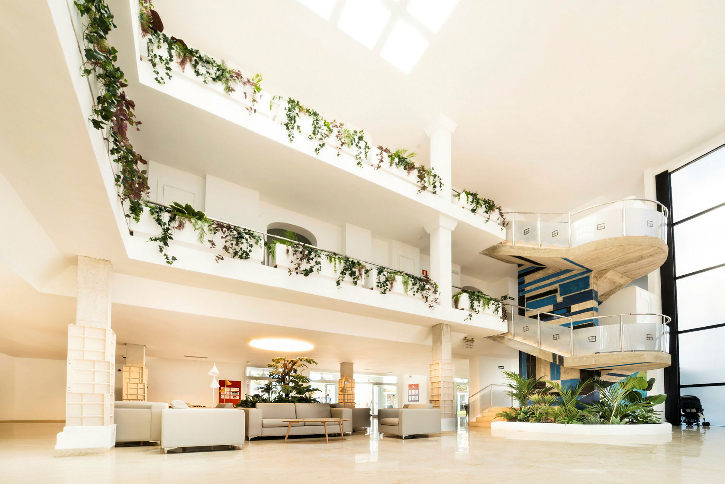 Interiør av romslig hotell med en spiraltrapp og frodige dekorasjoner. (AI-generert tekst)