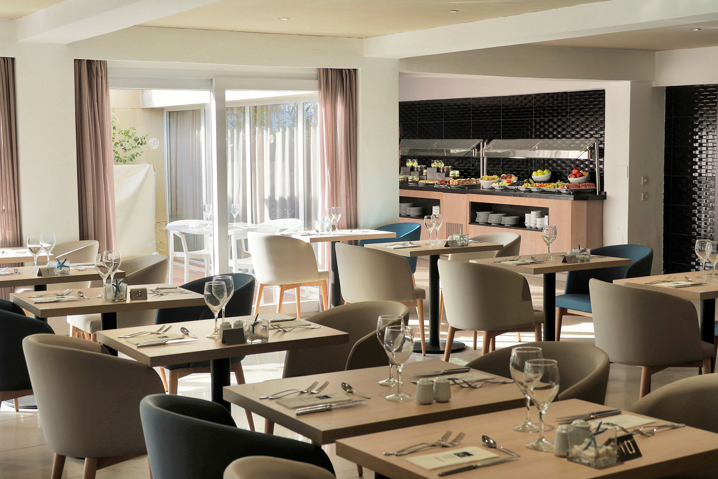 Bildet viser en moderne restaurant med bord og stoler, samt en buffet med mat. (AI-generert tekst)