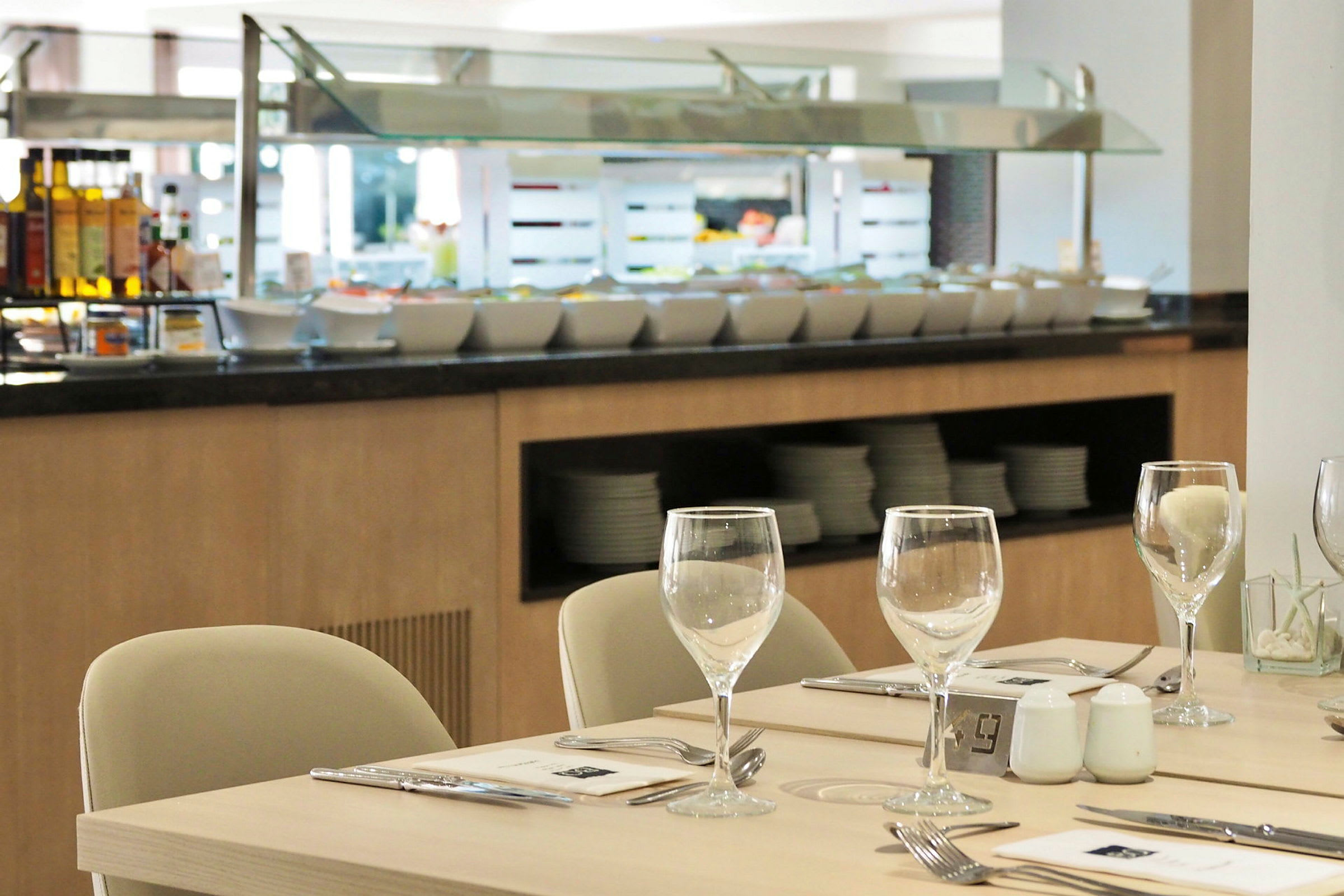 En restaurantbuffet med sitteplasser og dekkede bord i forgrunnen. (AI-generert tekst)