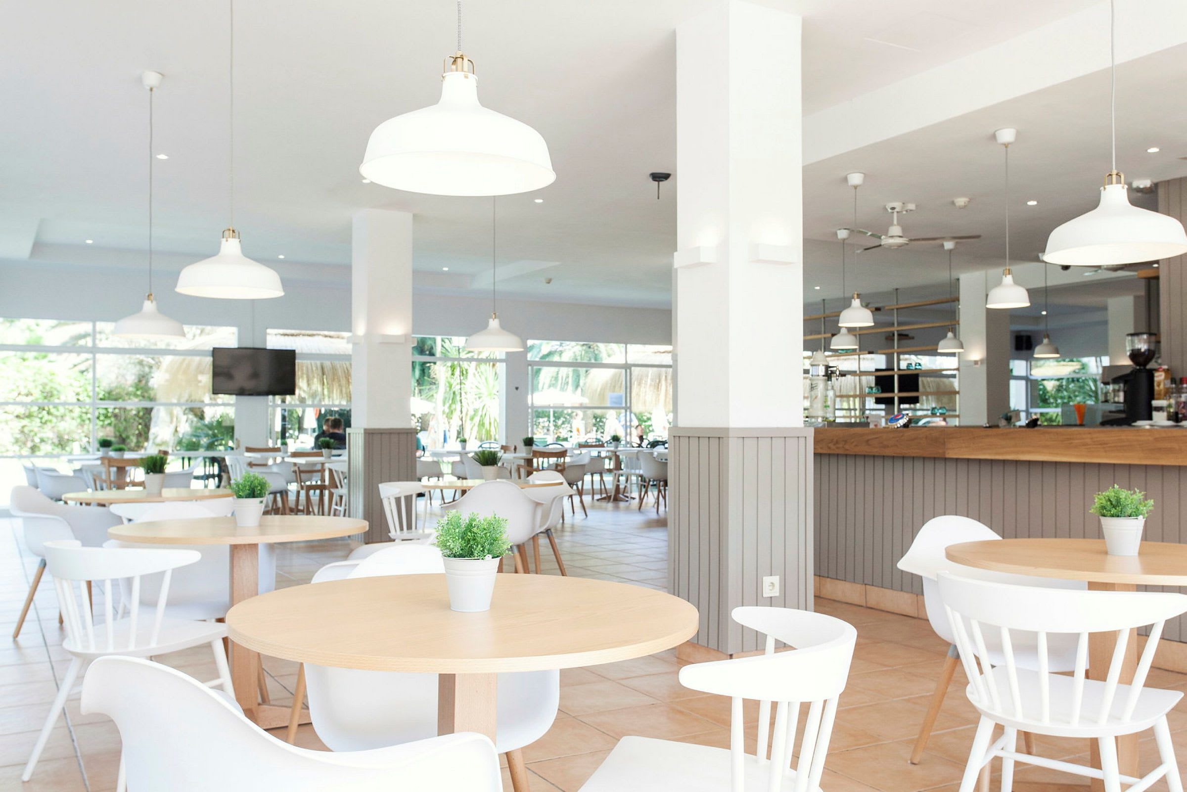 Bilde av en moderne, lys restaurant med bord, stoler og dekorative planter. (AI-generert tekst)