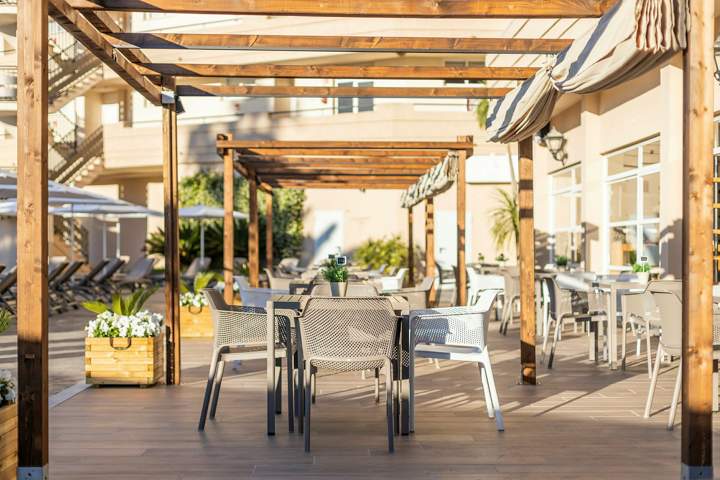Uteservering under trepergola med bord og stoler. (AI-generert tekst)