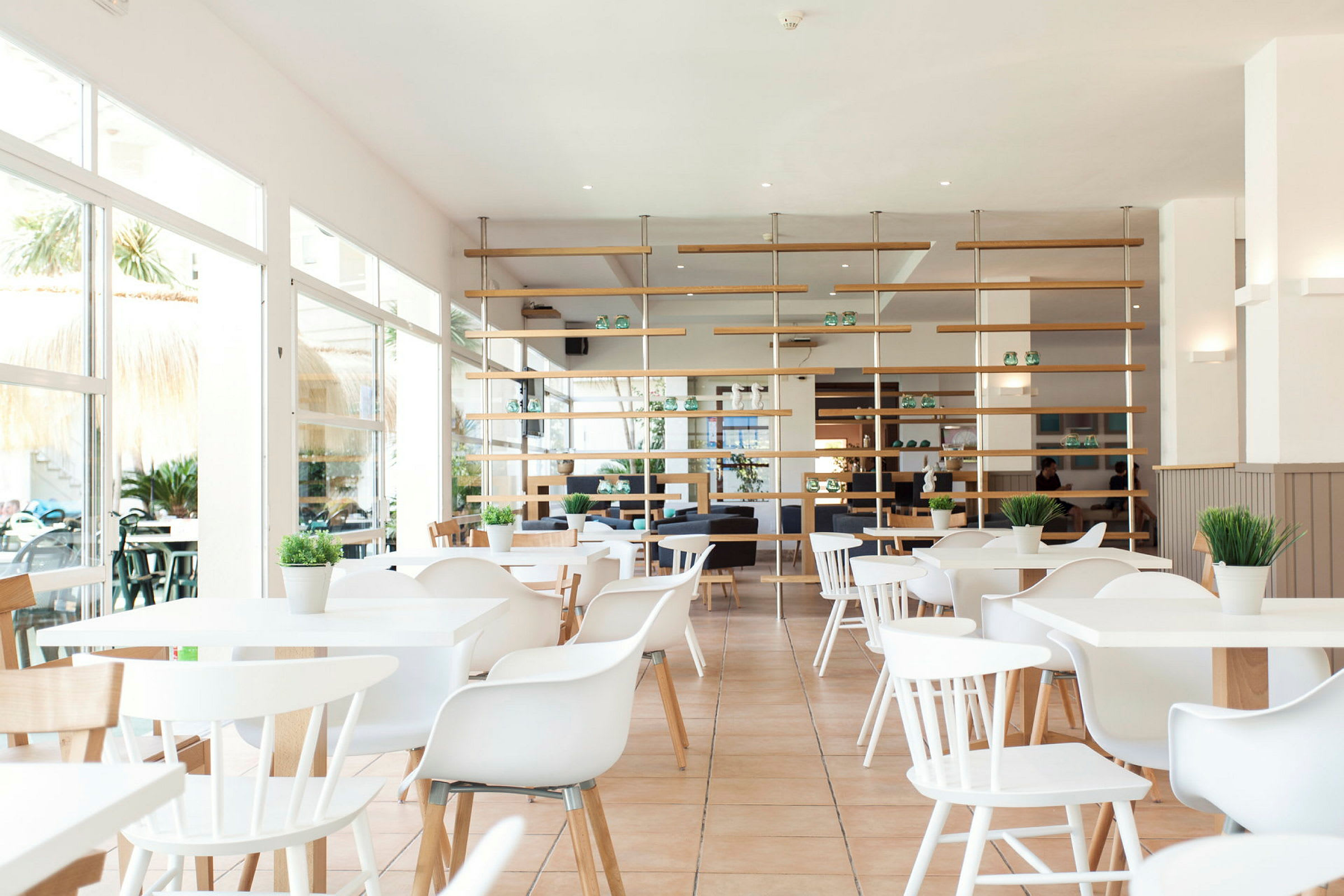 Lys og moderne restaurant med hvite møbler og grønne planter. (AI-generert tekst)
