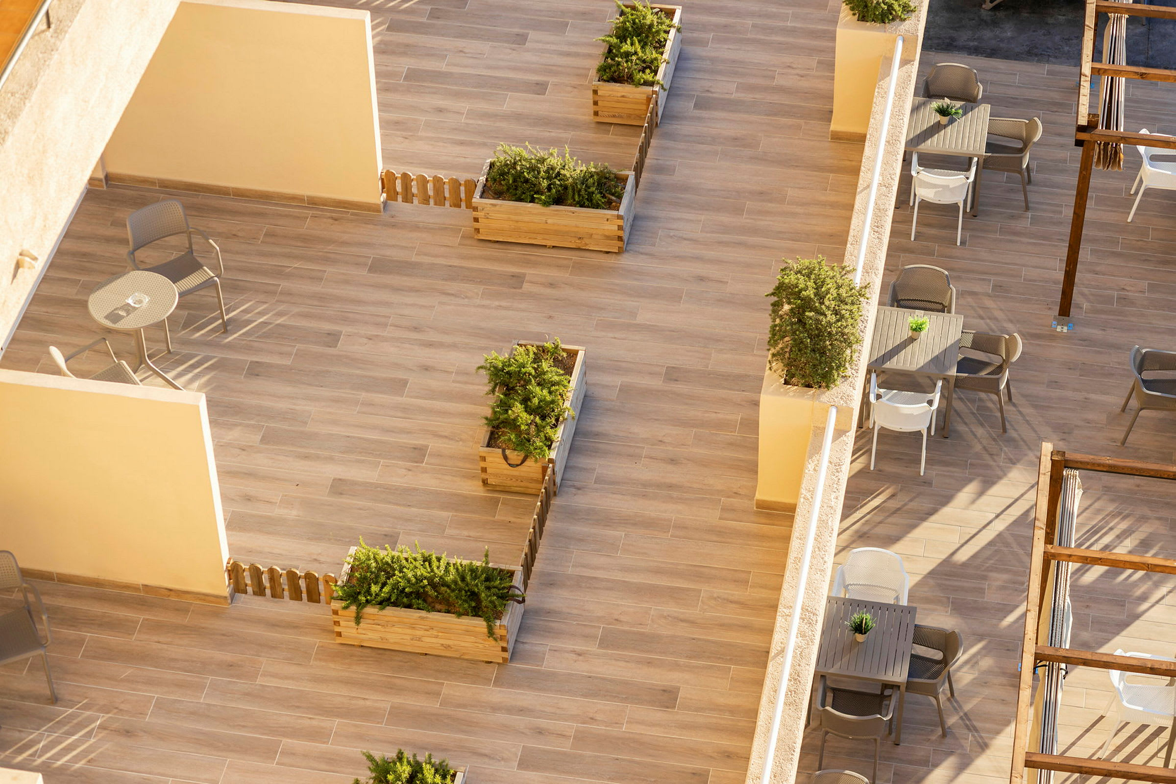 Utsikt over en terrasse med plantekasser, bord og stoler. (AI-generert tekst)