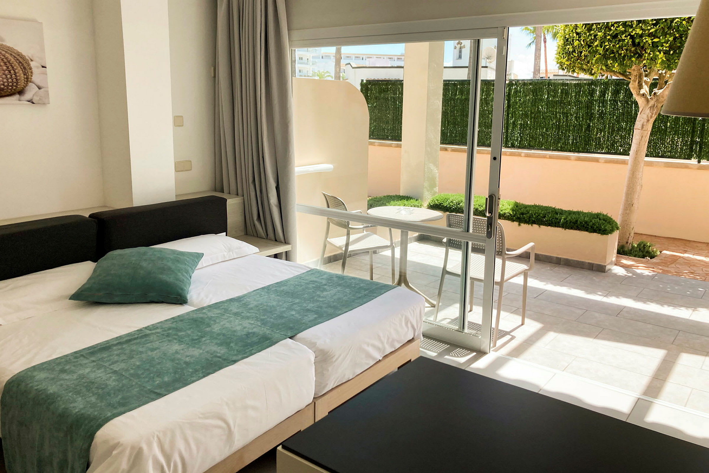 Moderne innredet hotellrom med seng og utsikt mot en privat terrasse. (AI-generert tekst)