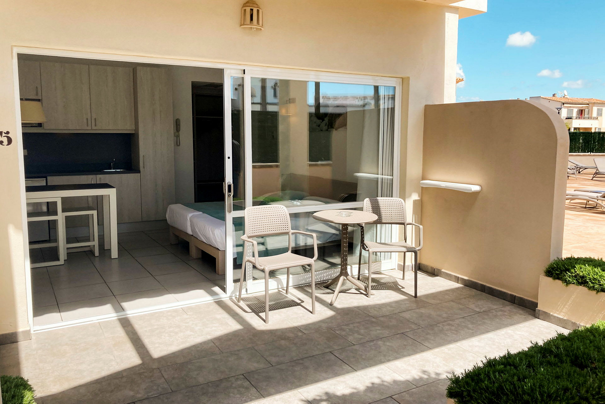 Terrasse med bord og stoler foran et hotellrom med glassdør. (AI-generert tekst)