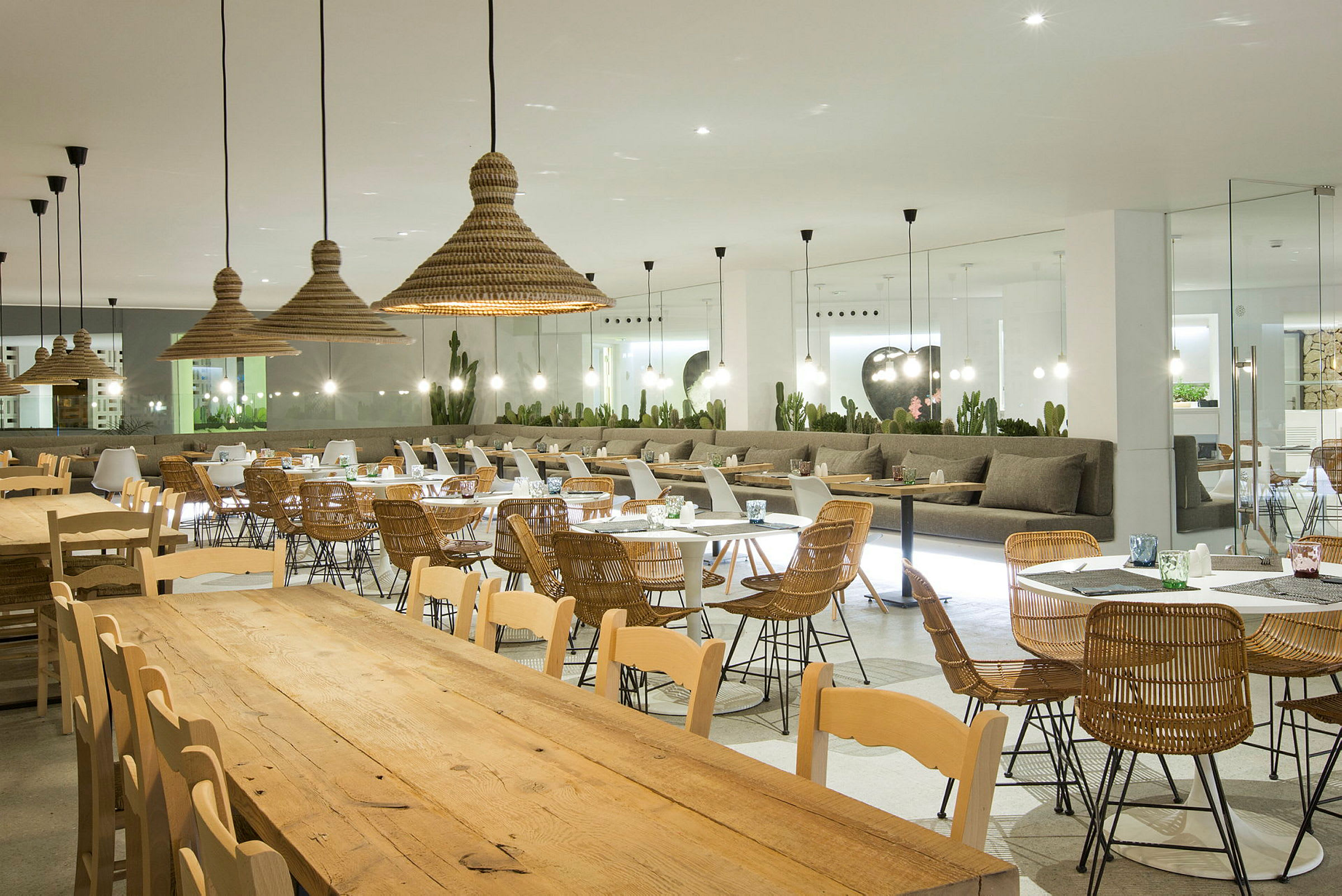 Åpen restaurant med bord og stoler av tre og rotting. (AI-generert tekst)
