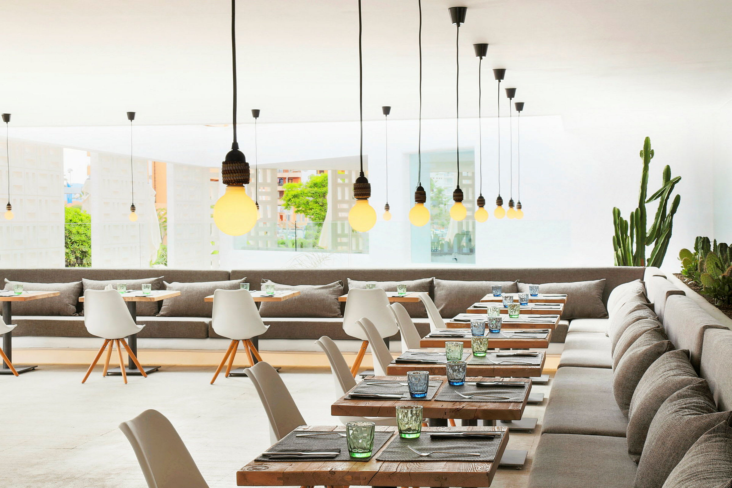 Restaurant med moderne interiør, bord og stoler samt hengende lamper. (AI-generert tekst)
