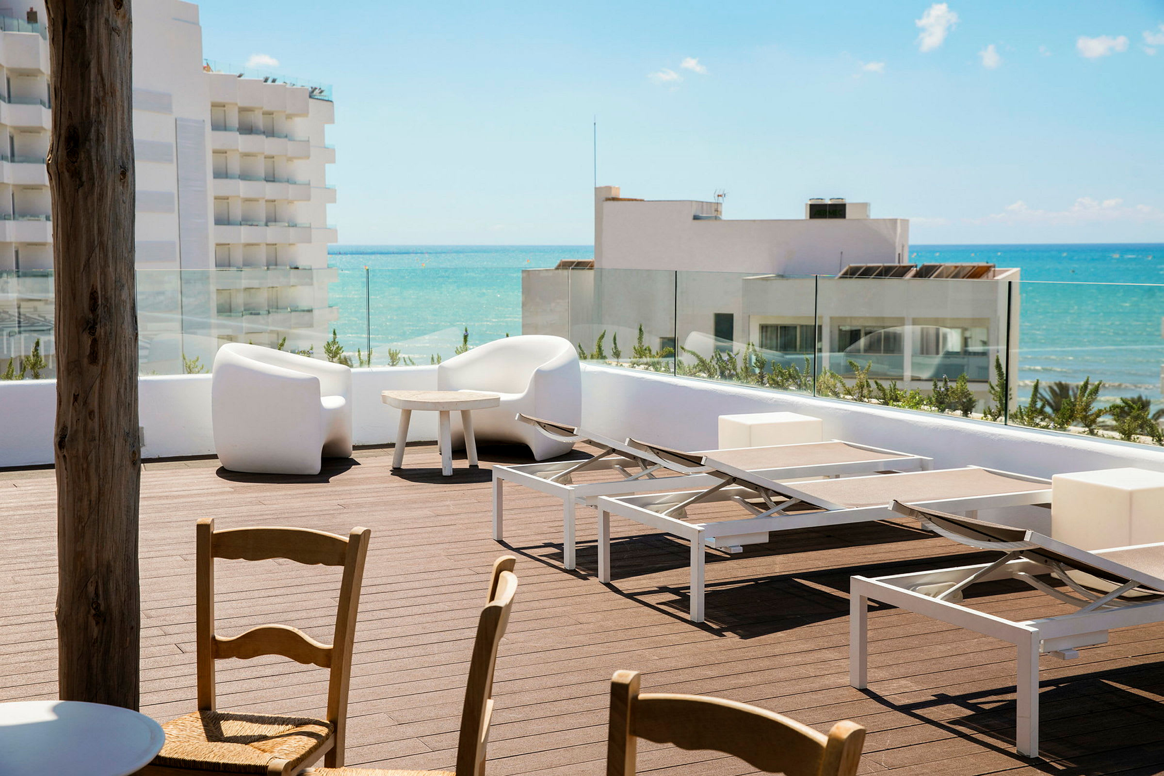 En solterrasse med solsenger og sitteplasser, med utsikt mot havet. (AI-generert tekst)