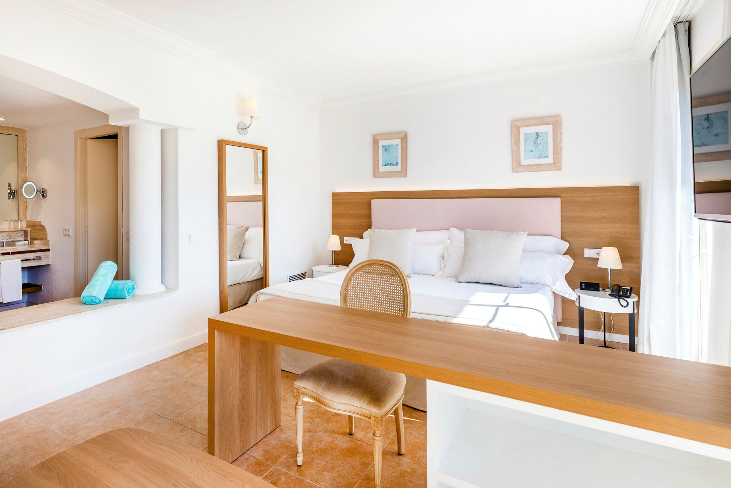 Lyst og romslig hotellrom med dobbeltseng, skrivebord og stol. (AI-generert tekst)