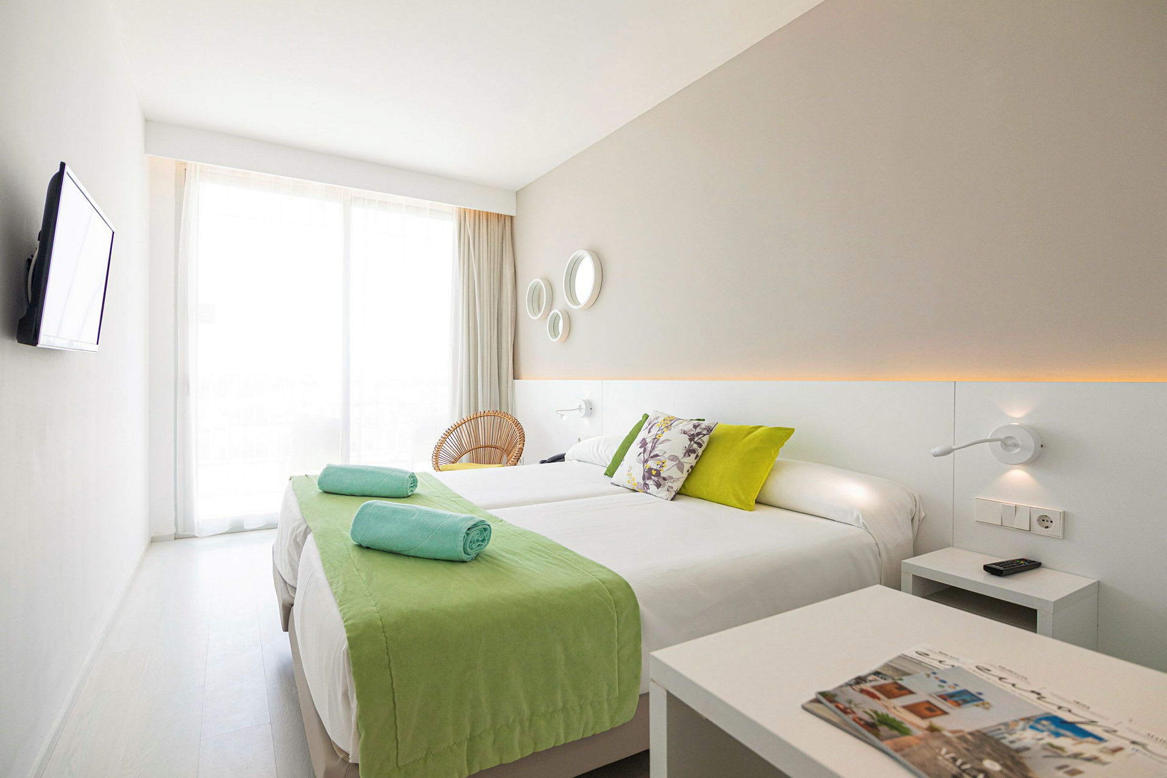 Et moderne hotellrom med to enkeltsenger og grønne detaljer. (AI-generert tekst)