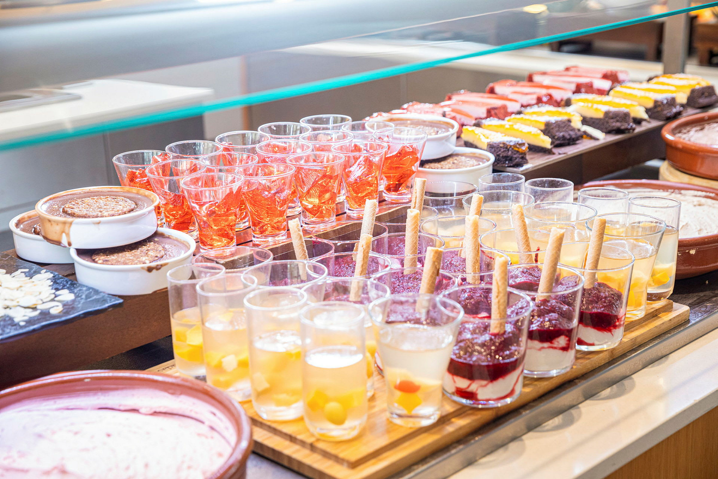 En buffet med forskjellige desserter, som glass med gelé og krem, samt kaker. (AI-generert tekst)