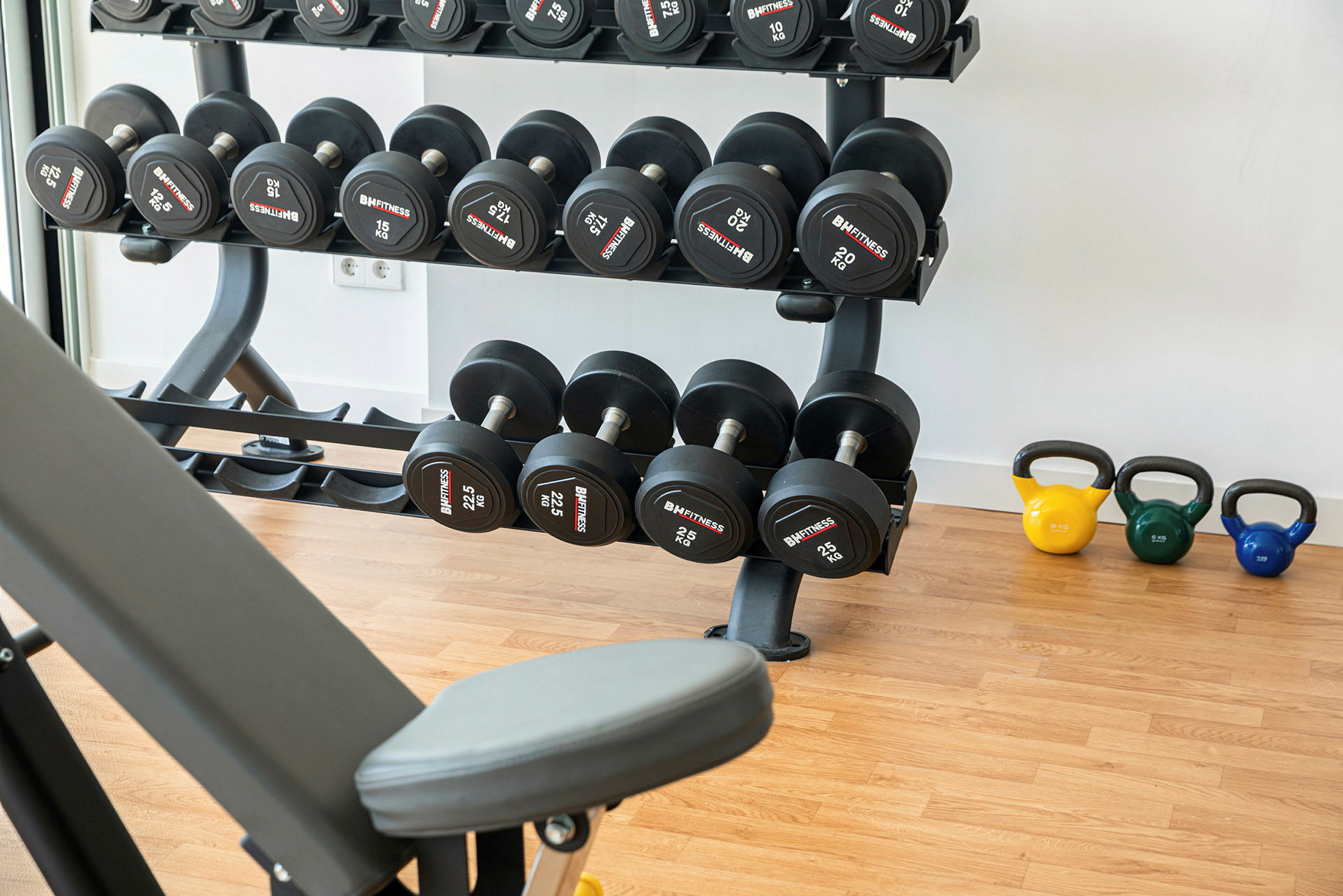 Gymutstyr med manualer og kettlebells på et tregulv. (AI-generert tekst)