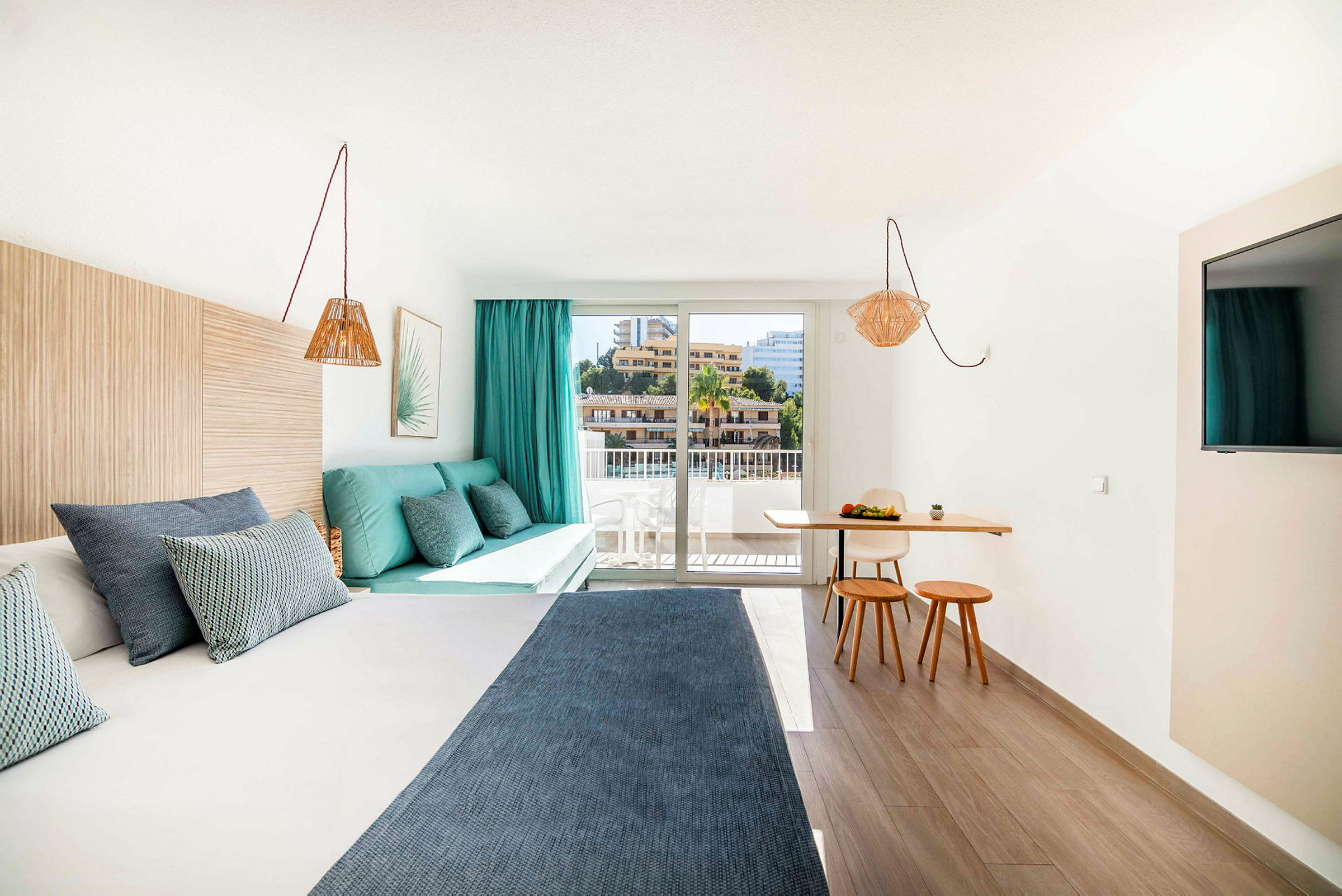 Et moderne hotellrom med en seng, en sittegruppe og en liten spiseplass ved et stort vindu. (AI-generert tekst)