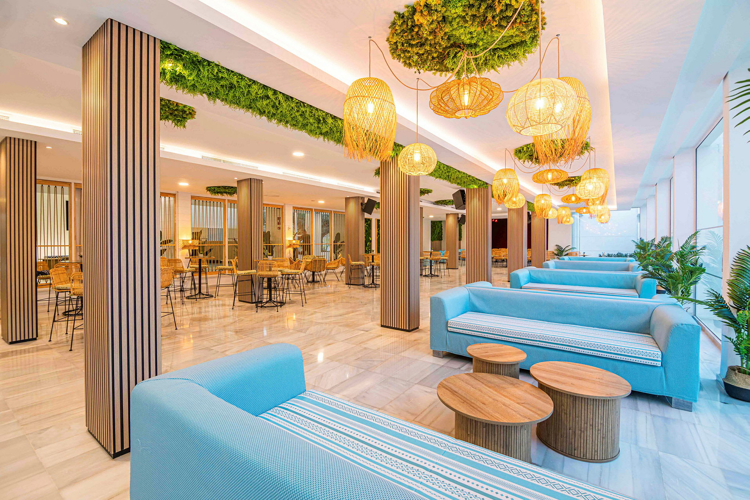 En moderne lounge med blå sofaer, trebord og designlamper i et lyst miljø. (AI-generert tekst)